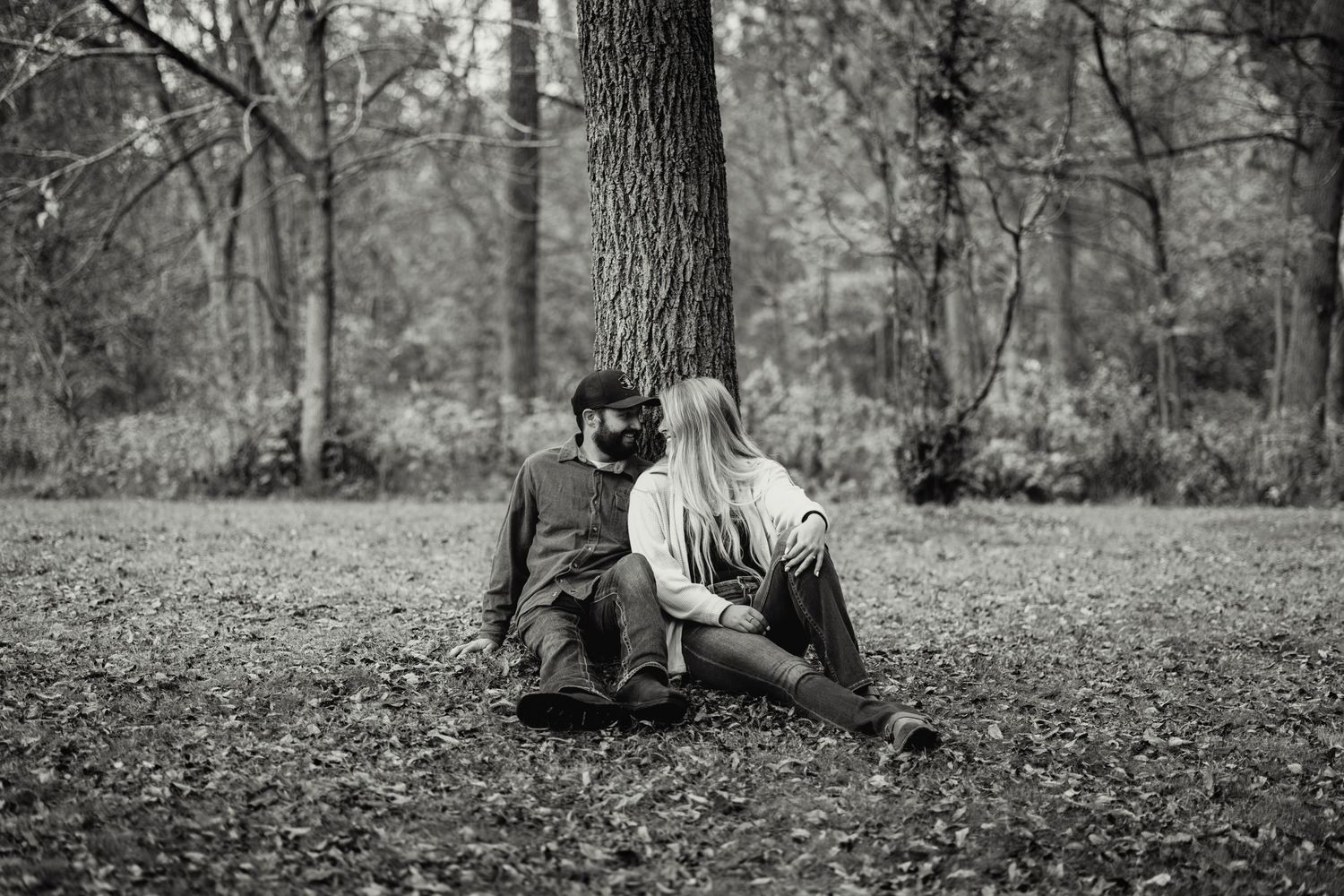 Black and white photo sequence showing a person sitting and leaning against a tree trunk in a wooded setting.
