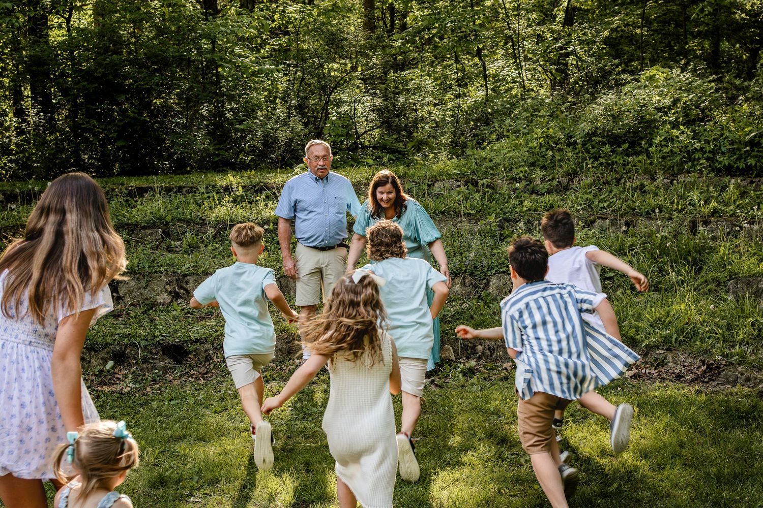 A group runs playfully through a green summer garden setting.