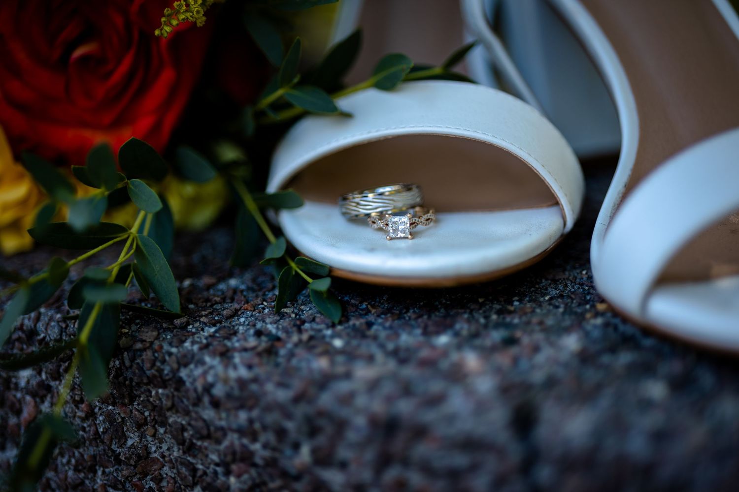 Wedding ring displayed on a rustic surface surrounded by delicate floral arrangements and soft lighting.