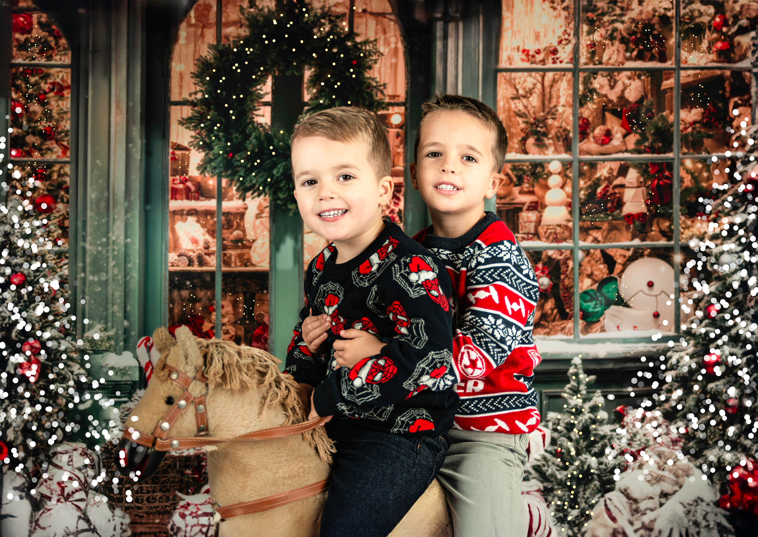 Three young children in matching red and black holiday sweaters pose together in front of a snowy winter backdrop.