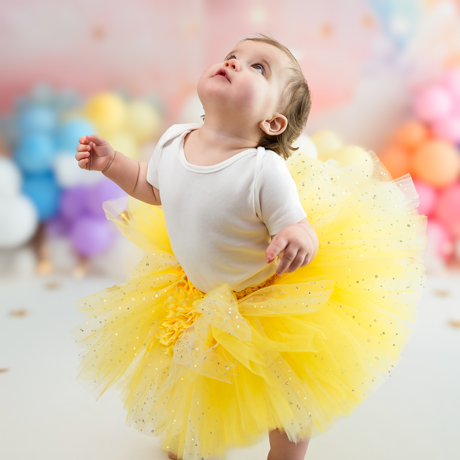 A child in a bright yellow tutu twirls and dances with joyful movement against a soft pastel background.