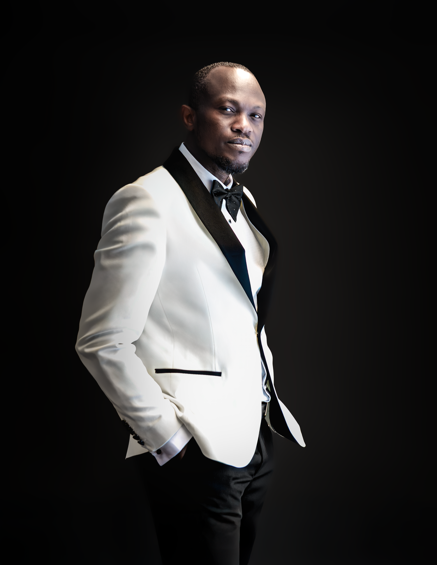 Sophisticated portrait of person in white dinner jacket against black backdrop.