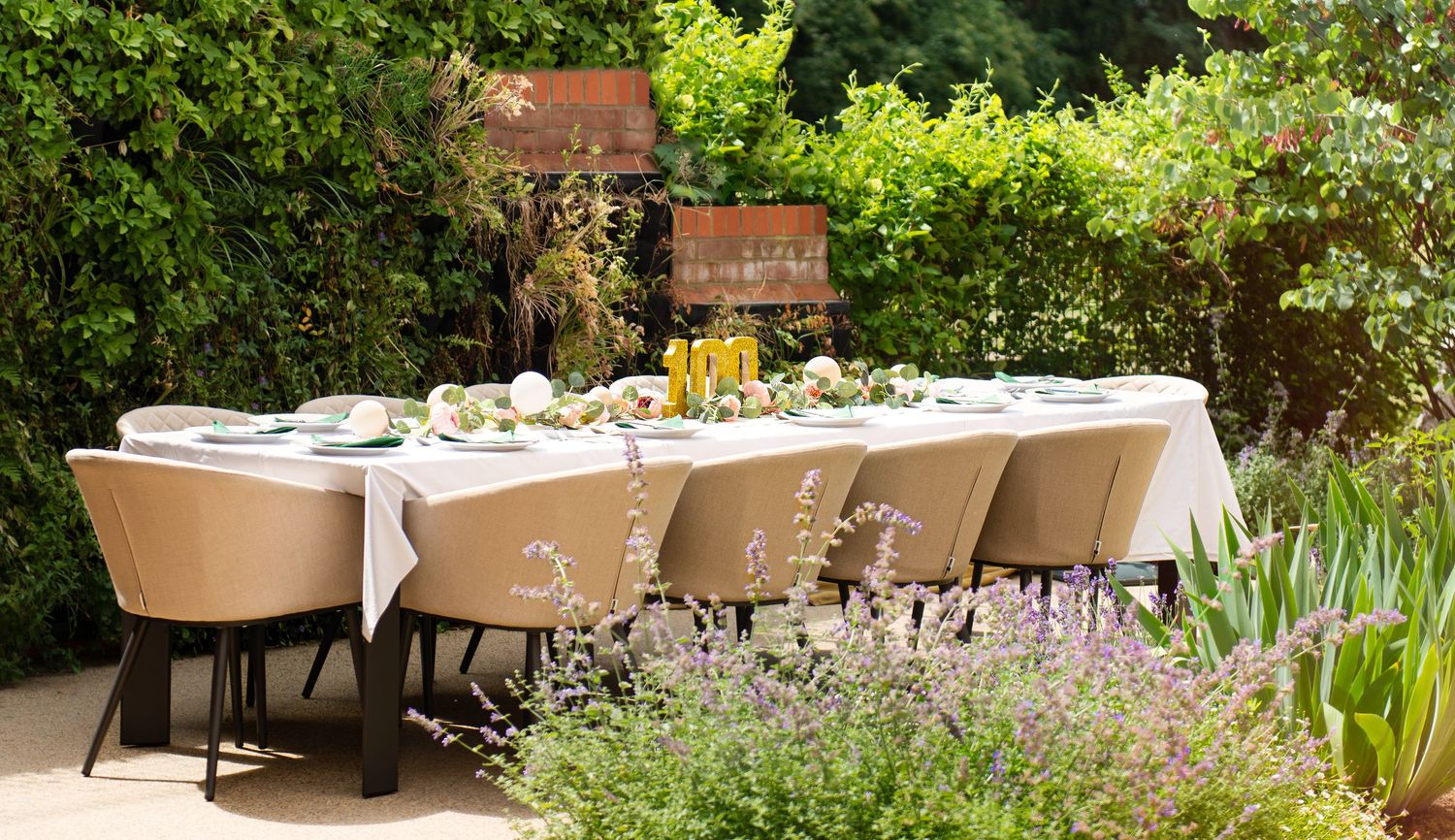 Lush garden setting with outdoor dining tables and natural landscaping.