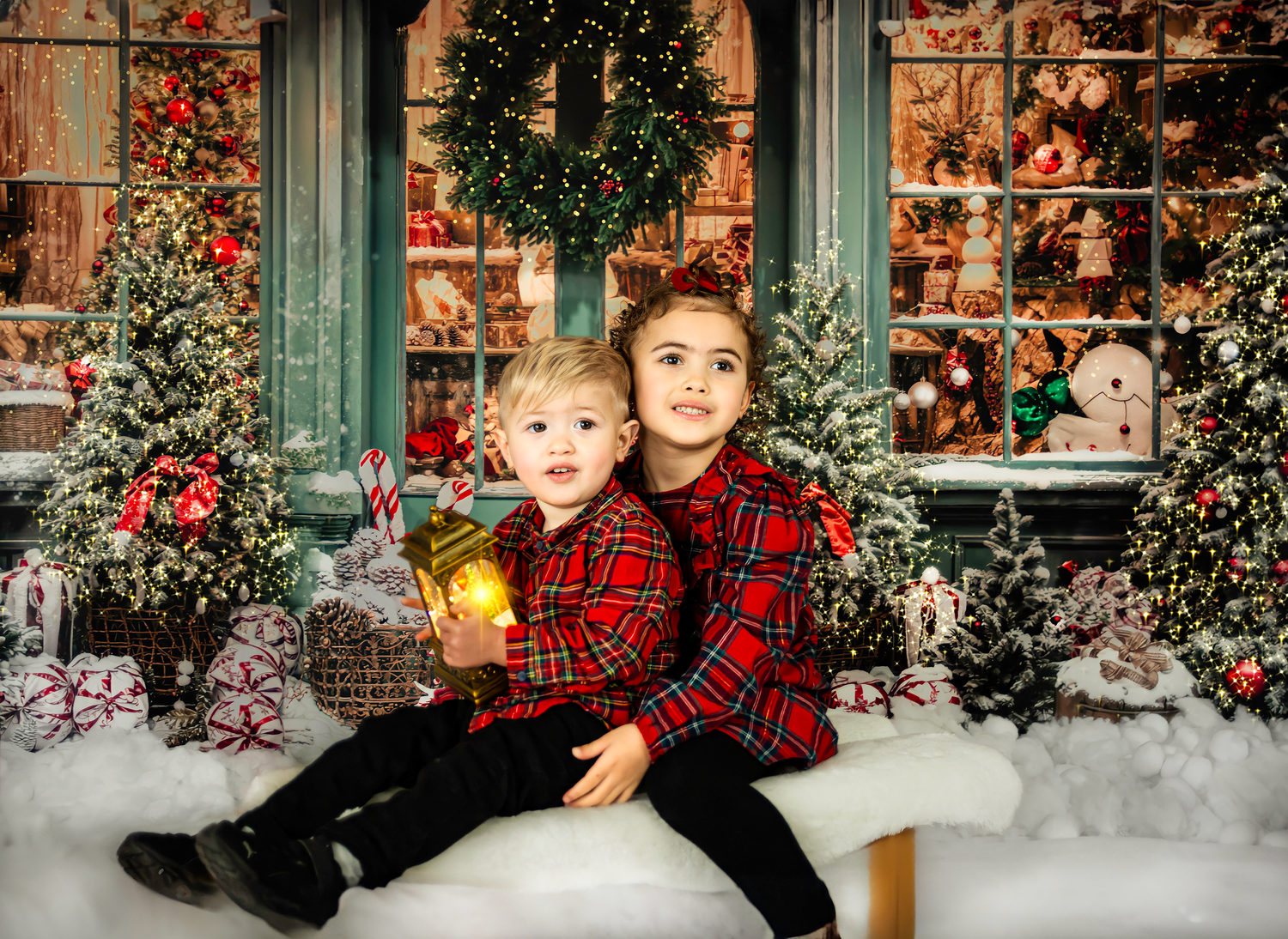 Festive holiday photoshoot setup with decorated Christmas trees, snow, and green window frames in a cozy studio setting.