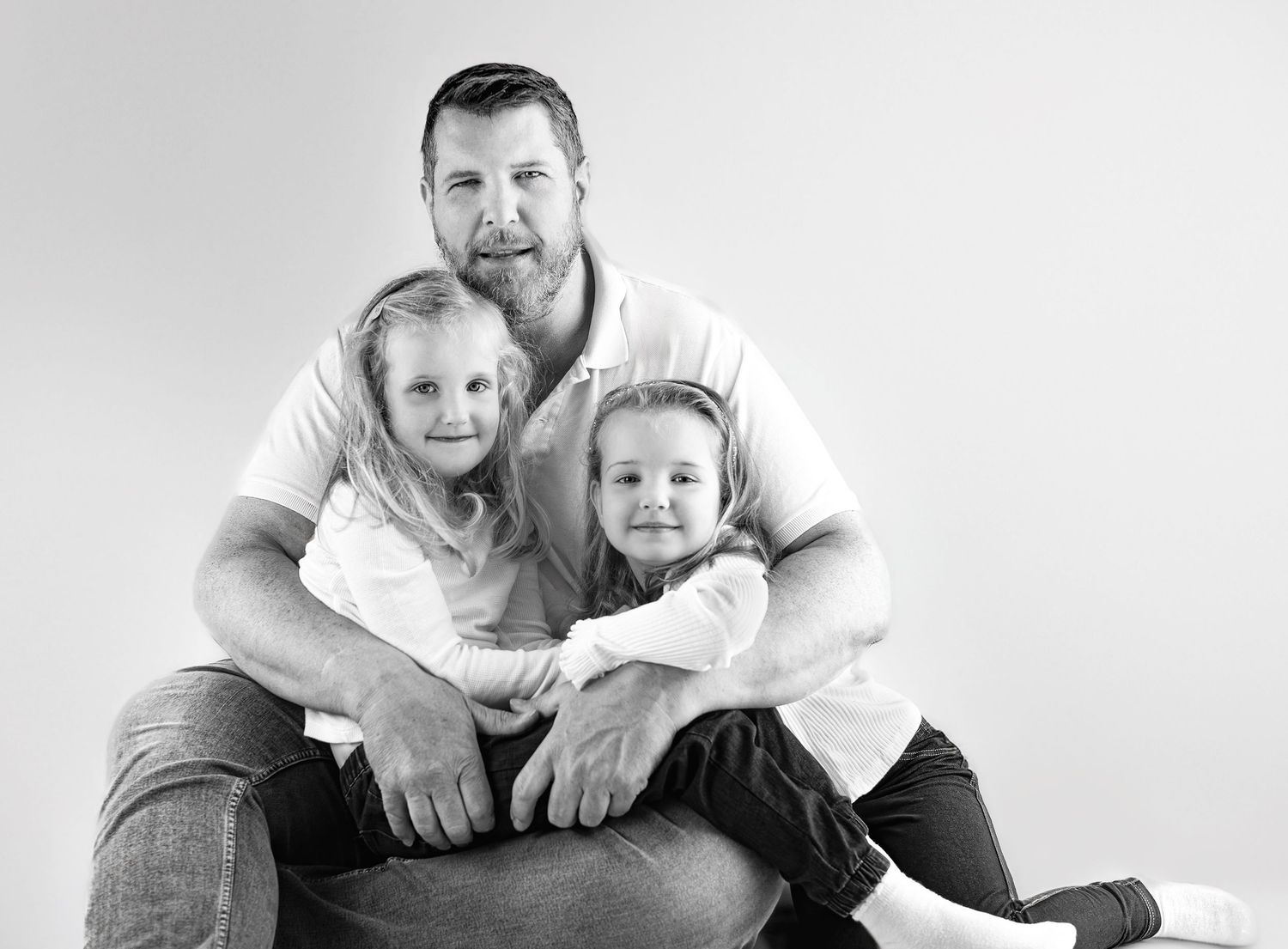 Black and white family portrait series showcasing casual poses and genuine expressions.