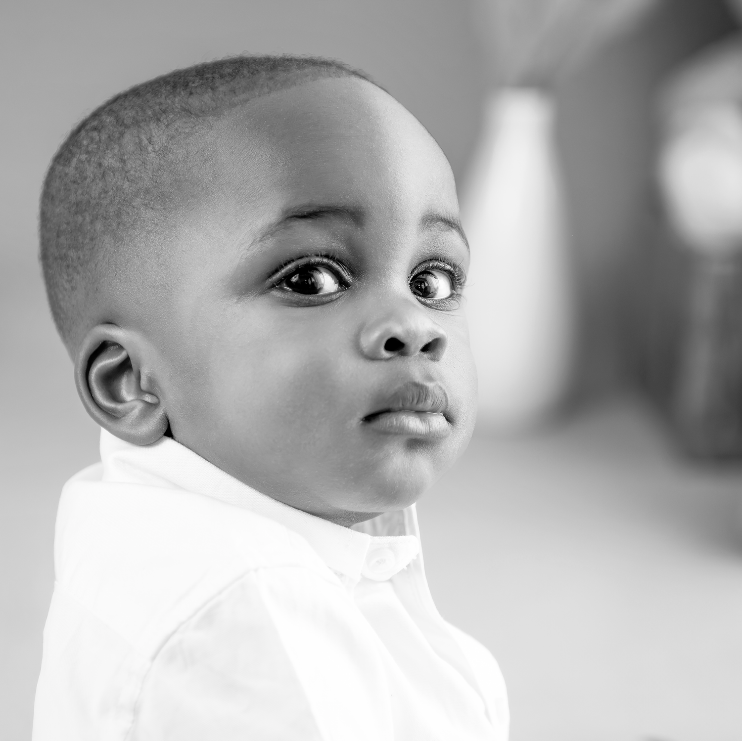 A black and white portrait series showing a young child in a white shirt looking in different directions.