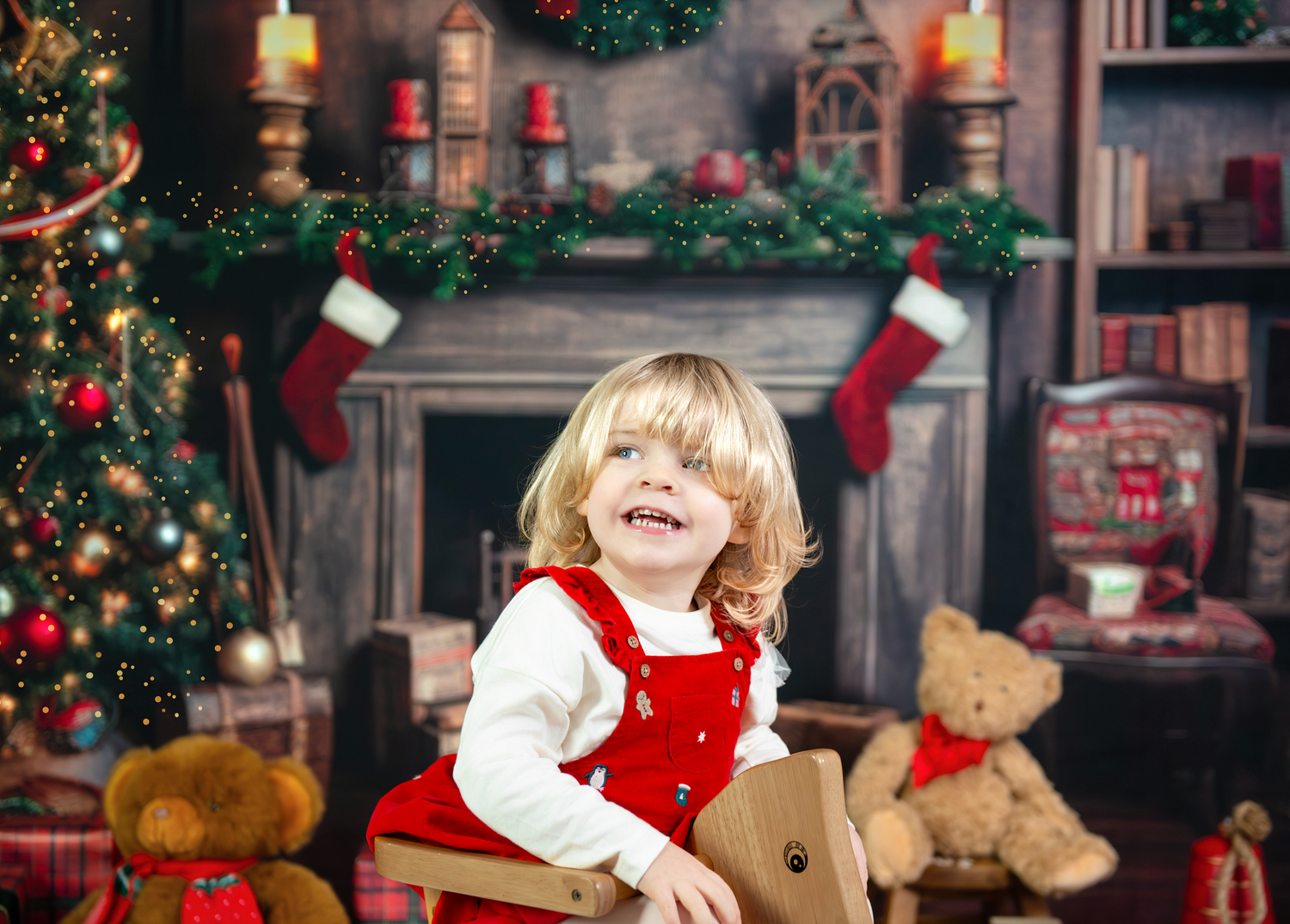 A child in festive red and white attire laughs joyfully while sitting by a decorated Christmas tree and fireplace.