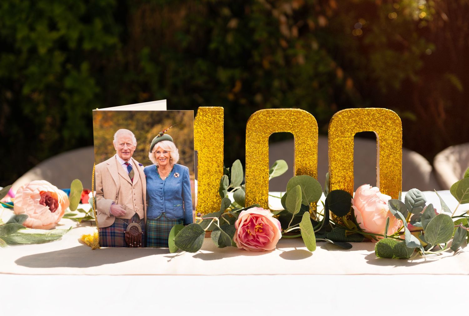 Outdoor party setting with gold letter decorations and floral arrangements.