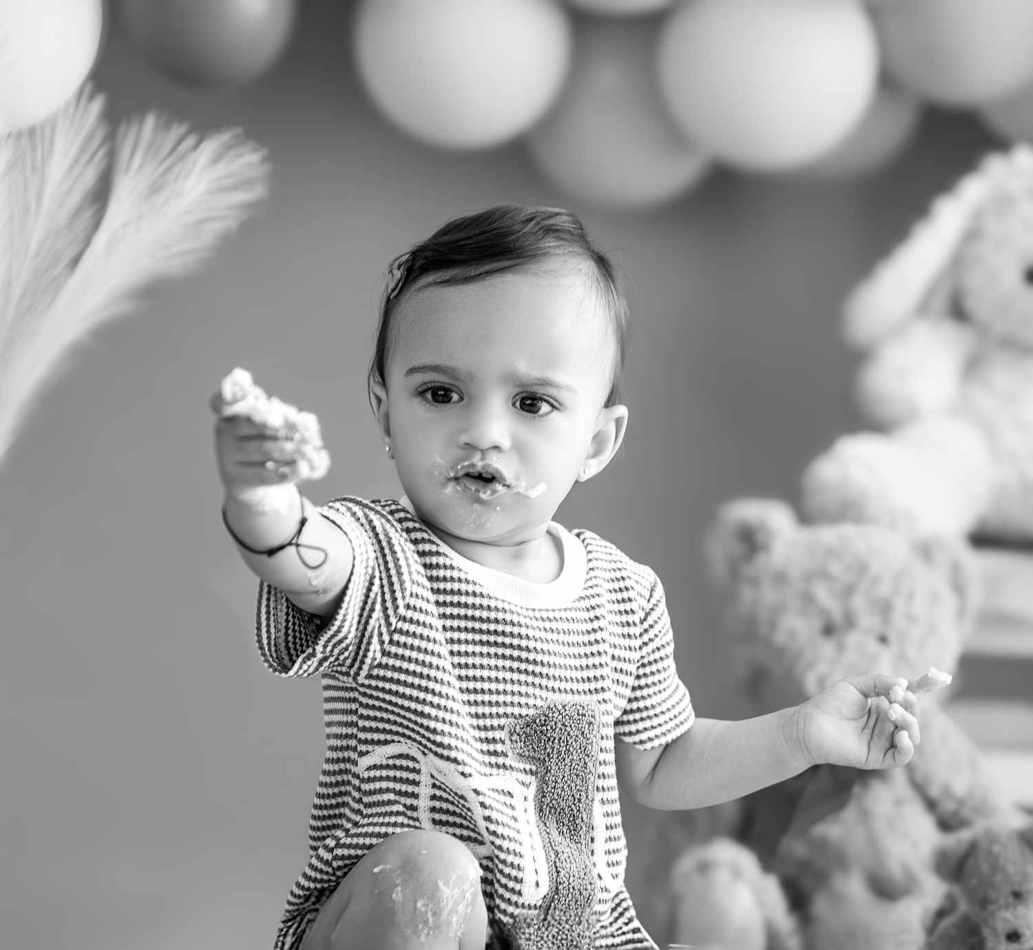 Black and white photo series showing a baby in striped clothing playing with stuffed animals and toys.