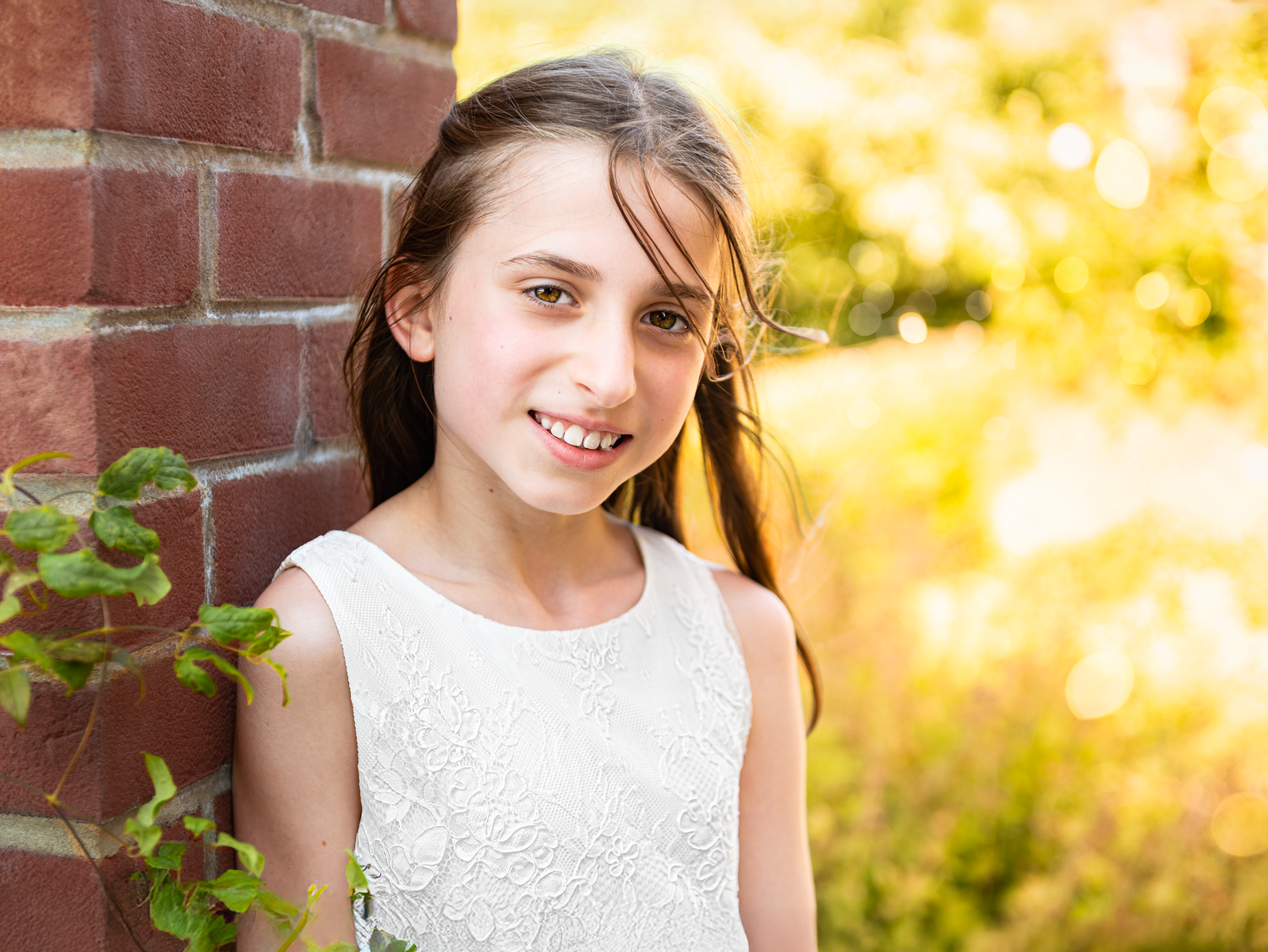 Young person in a white dress captured against a warm golden sunset.