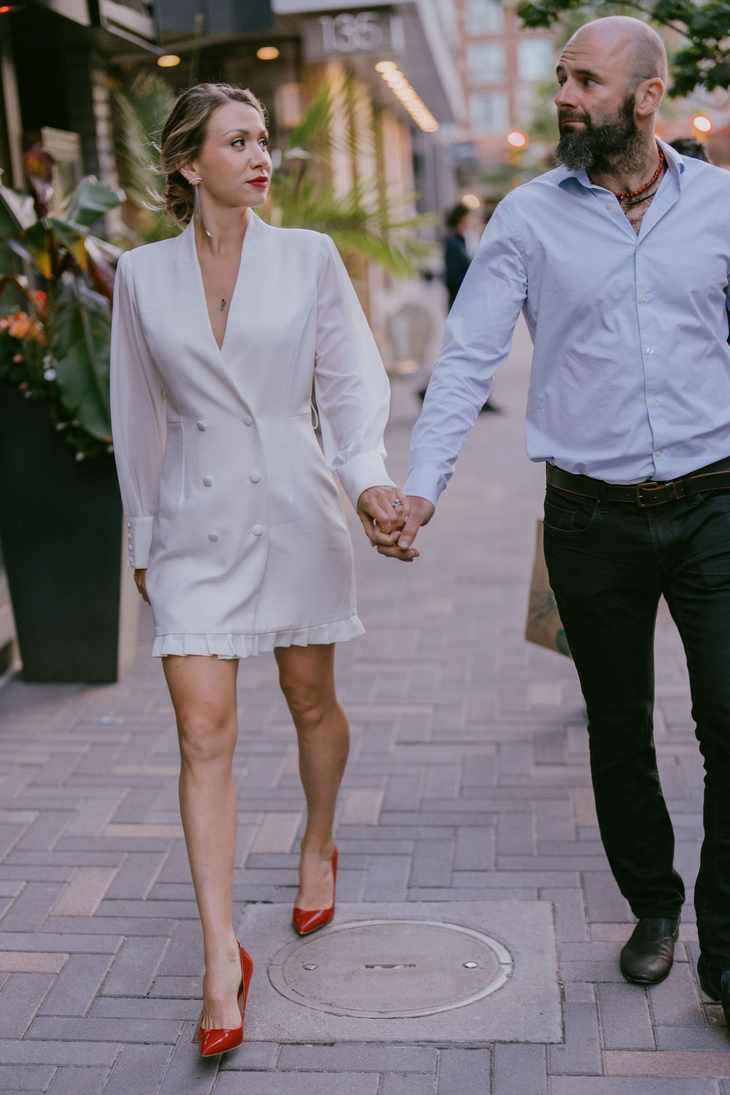 Engagement photo of couple walking hand-in-hand down a charming city street