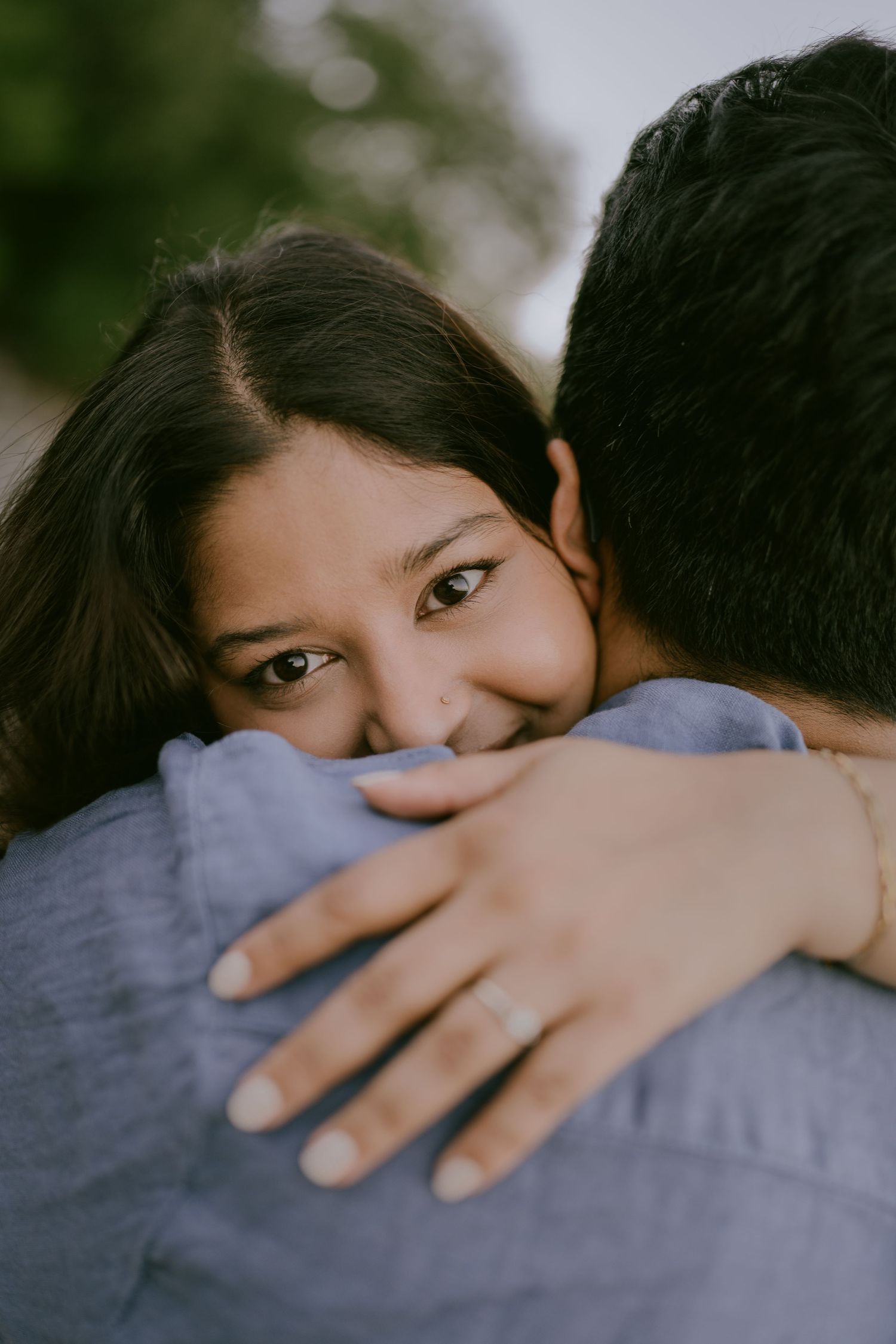 Close-up of woman hugging her partner and smiling over his shoulder