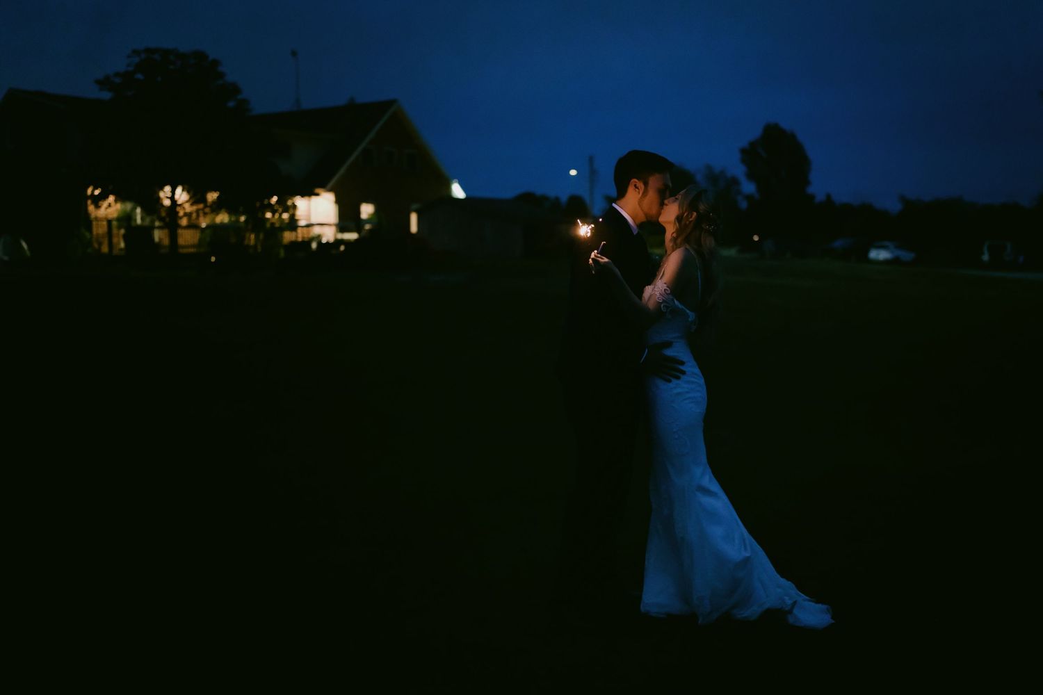 Bride and groom sharing romantic sparkler moment in evening light