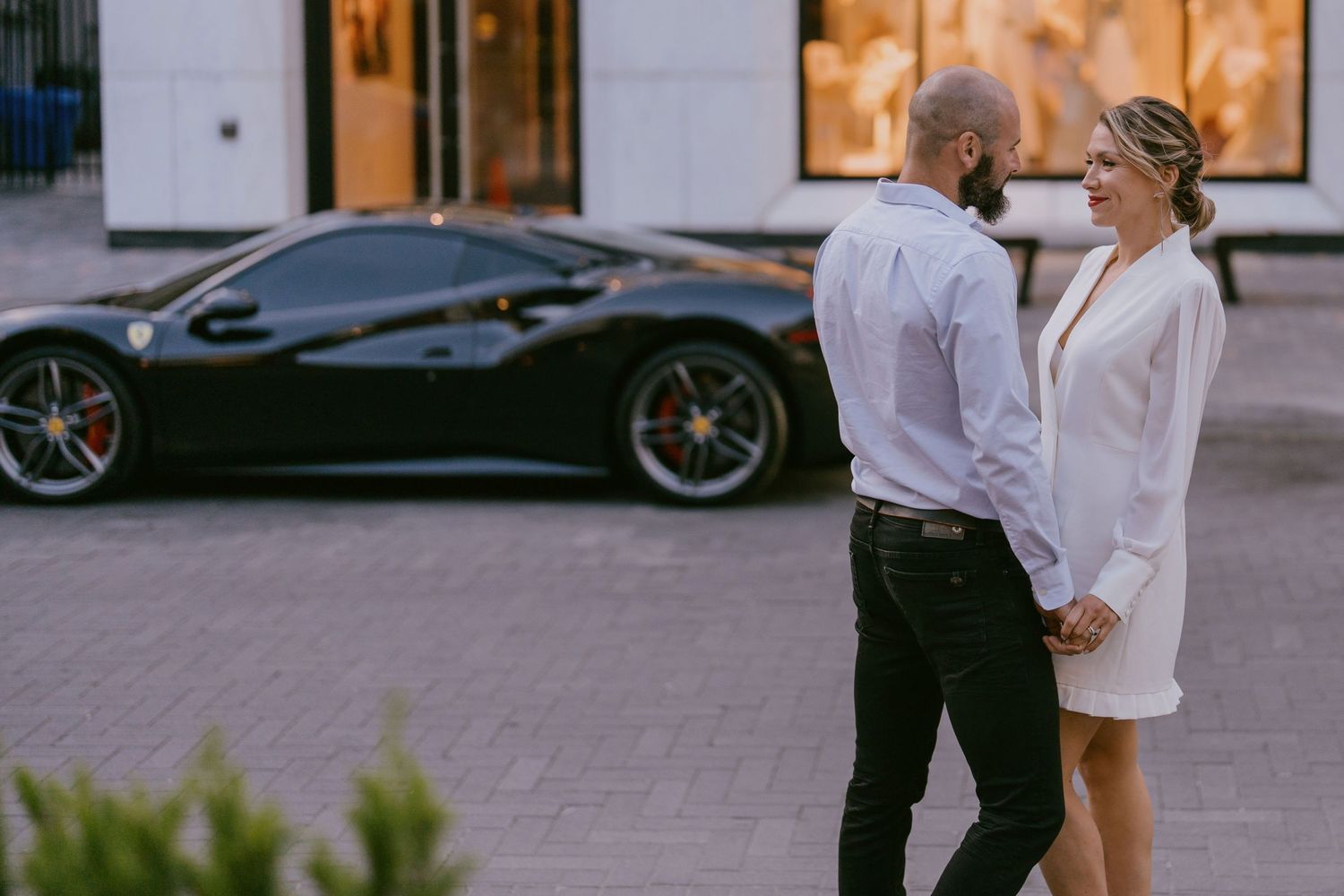 Chic couple standing together in front of a luxury sports car during a downtown shoot