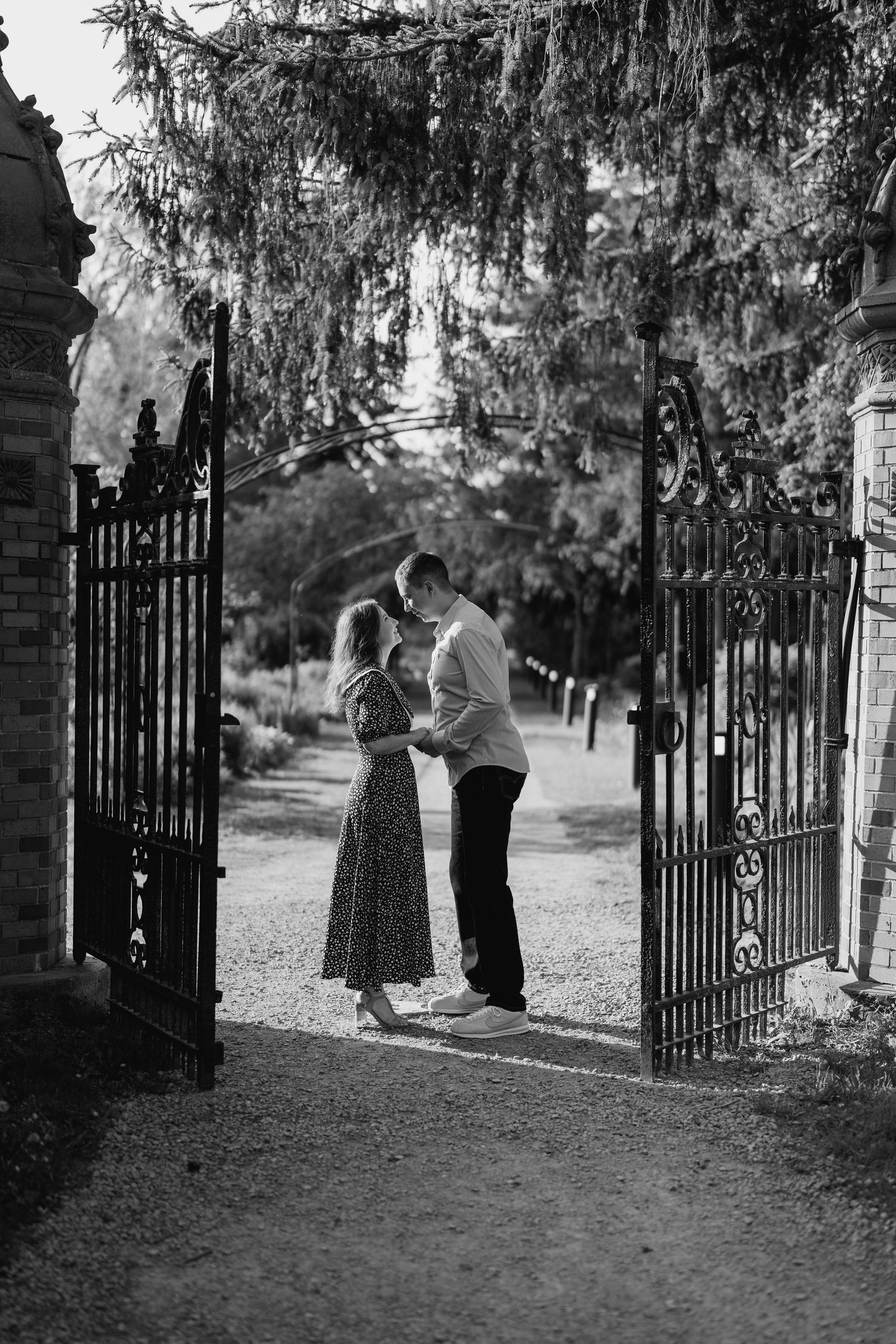 Black and white romantic photo of couple kissing under antique garden gate  in Toronto
