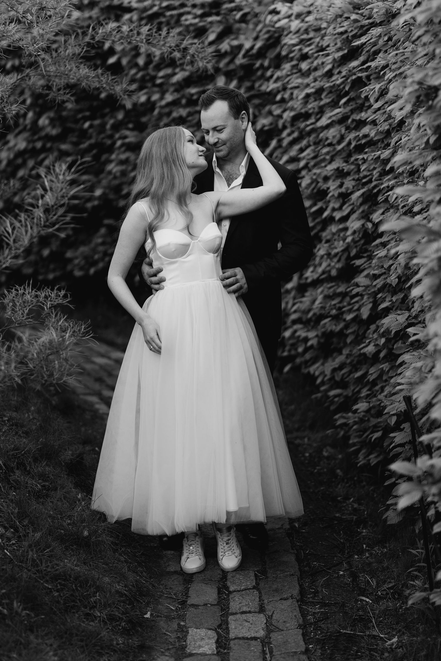 Elegant black and white portrait of bride and groom walking a garden path  in Oshawa, available throughout Toronto and Durham region