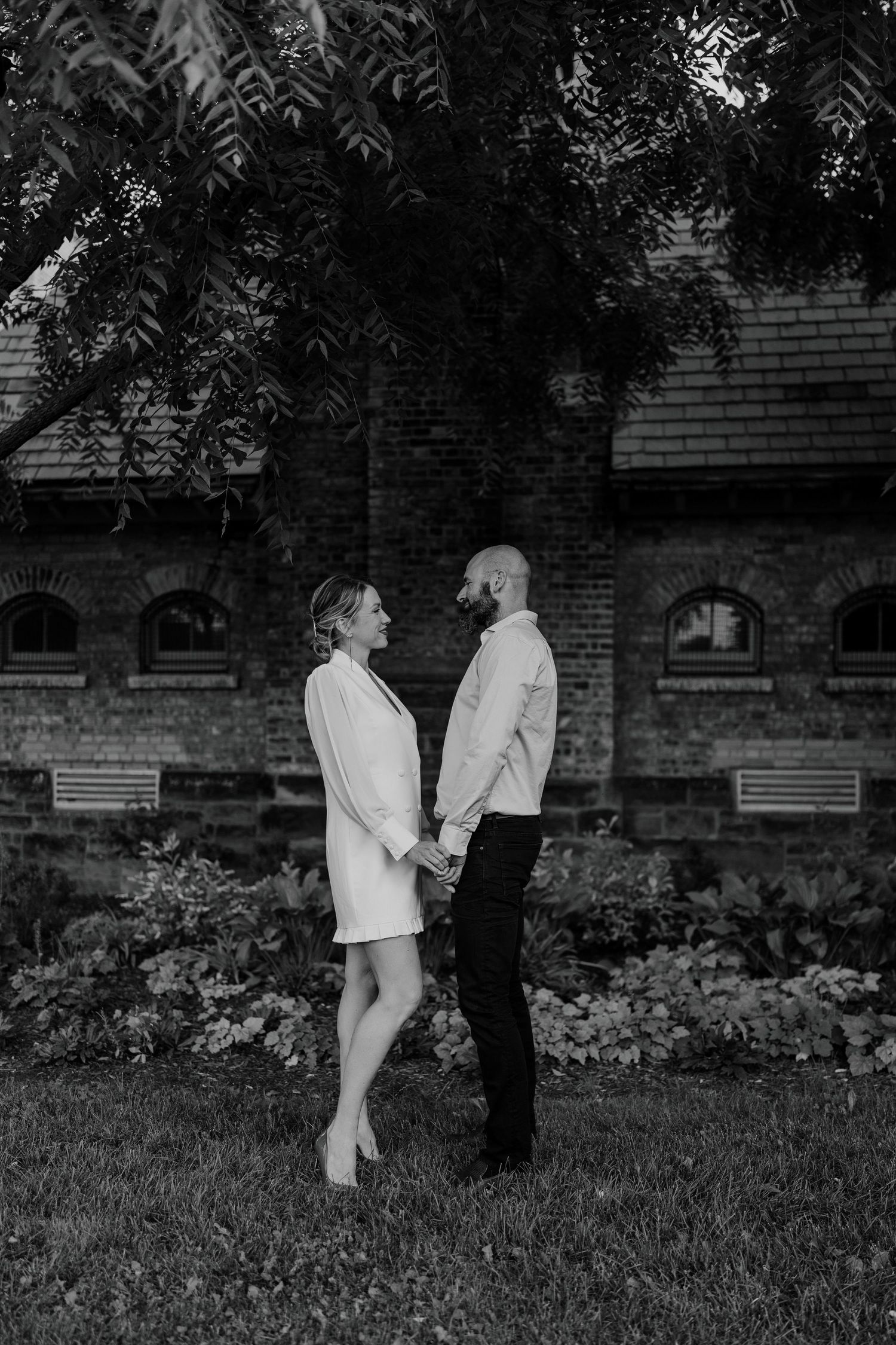 Black and white photo of couple walking hand-in-hand through quiet garden