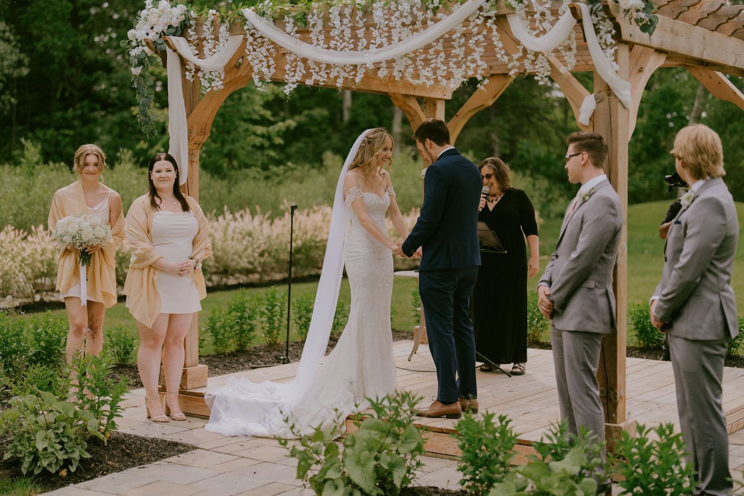 Bride and groom at altar during vows with bridal party looking on