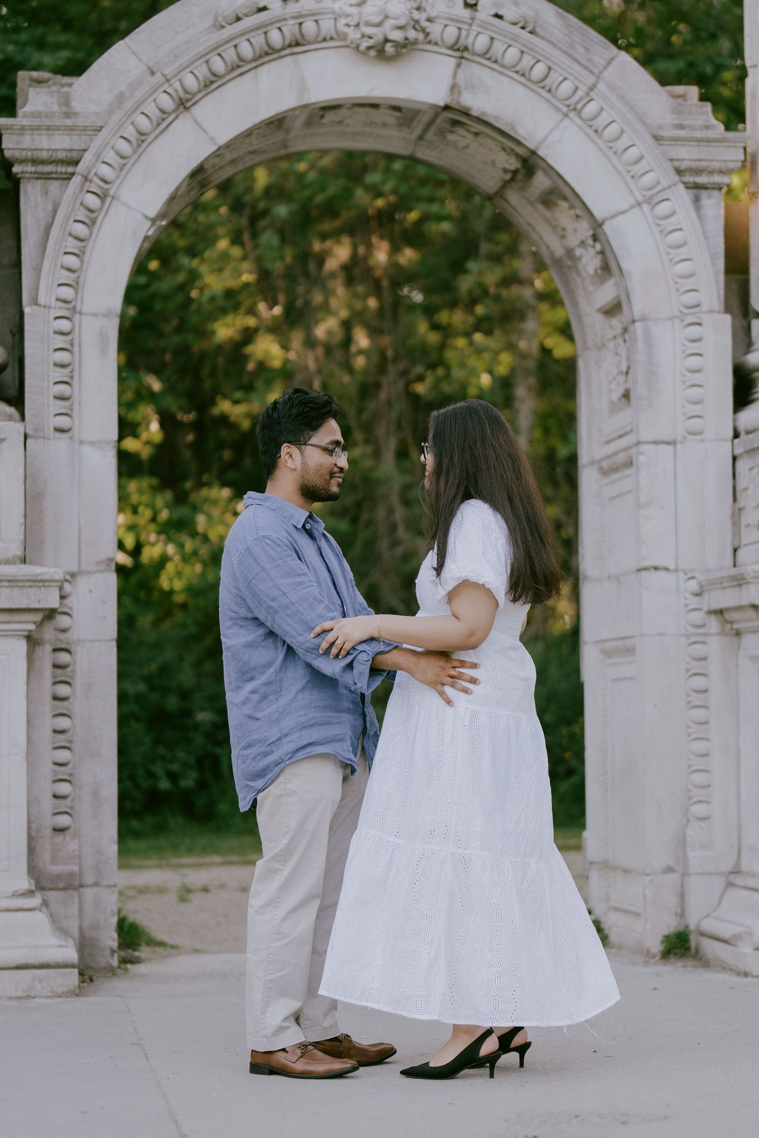 Romantic engagement photo of couple standing beneath carved stone arch