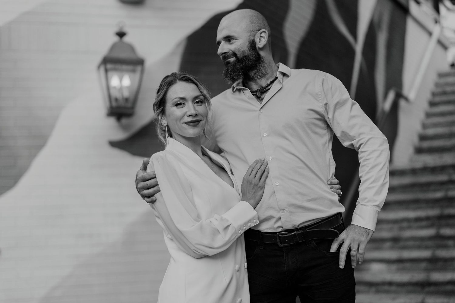 Artistic black and white portrait of couple posing in front of a painted wall mural