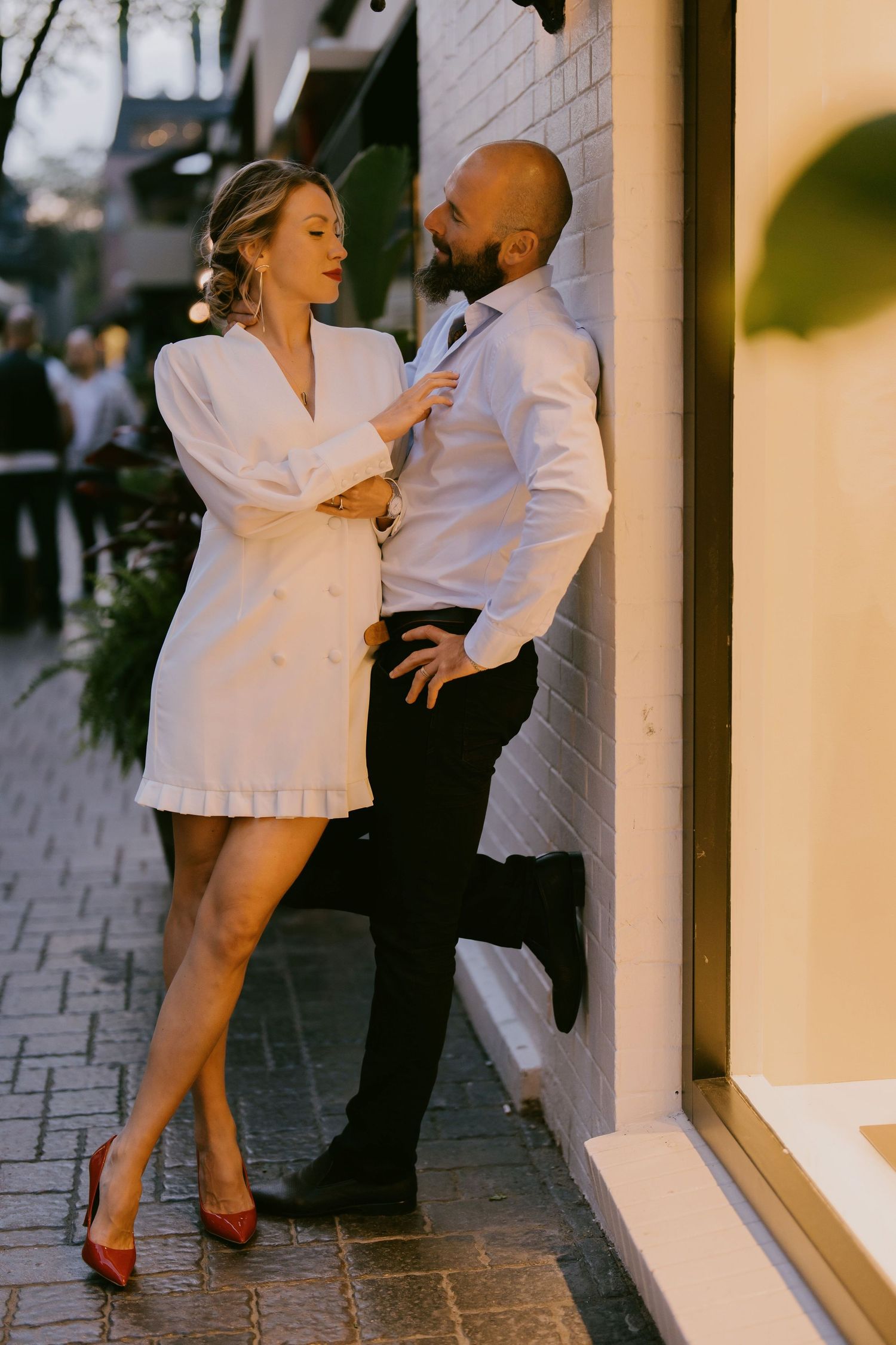 Fashion-forward engagement photo of couple posing in front of store window downtown
