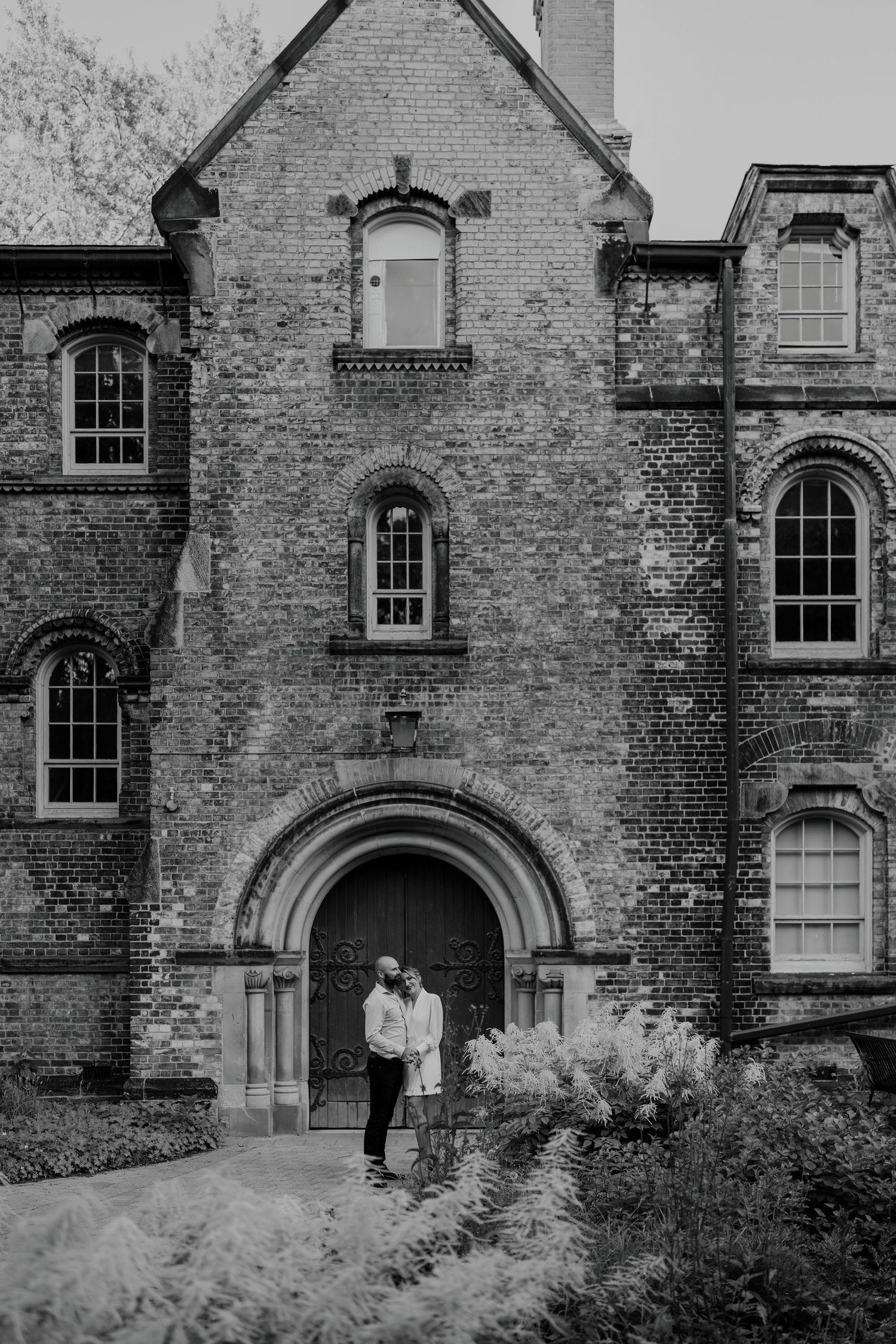 Cinematic wide photo of couple in front of tall historic brick building