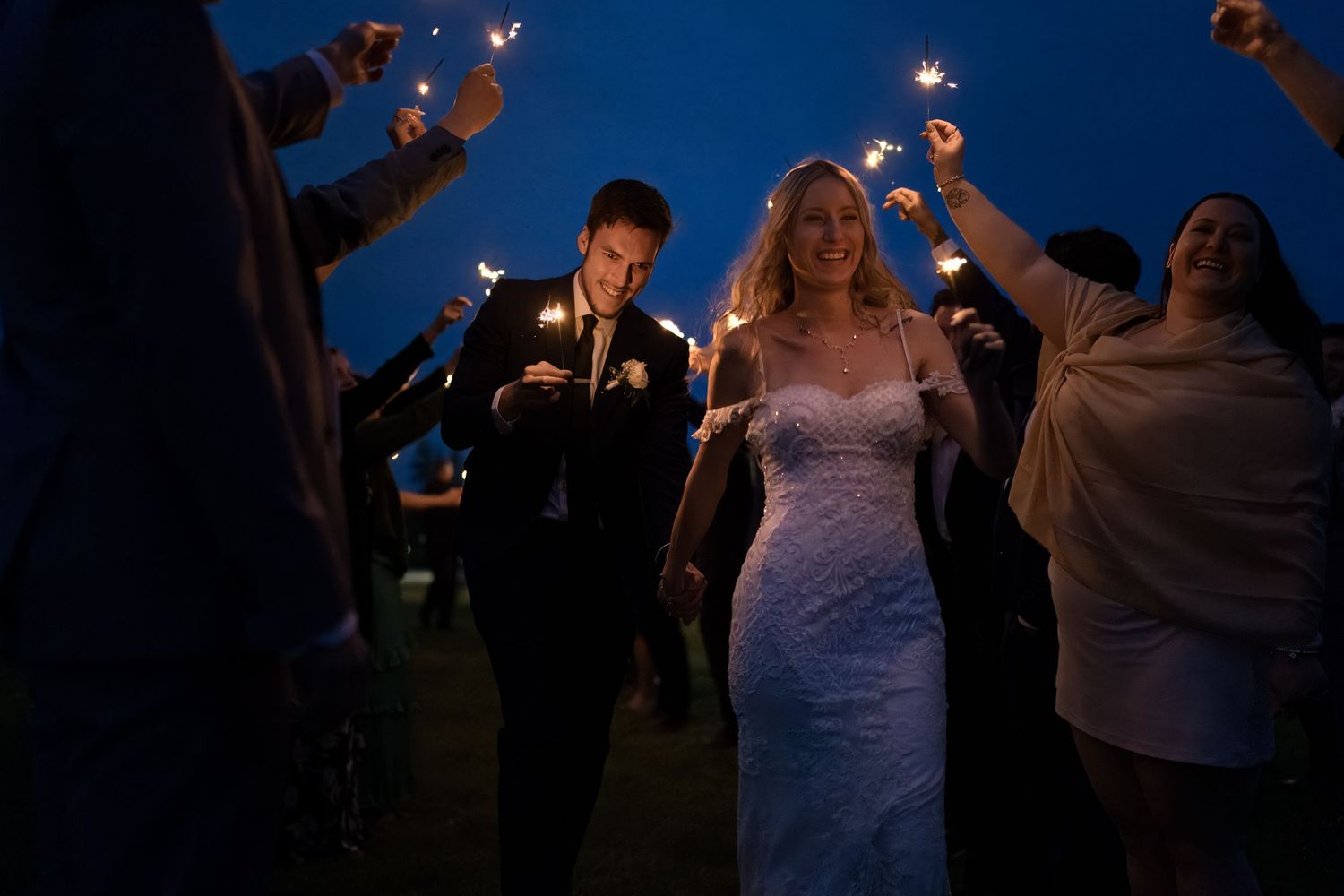 Bride and groom walking through sparkler tunnel for evening send-off