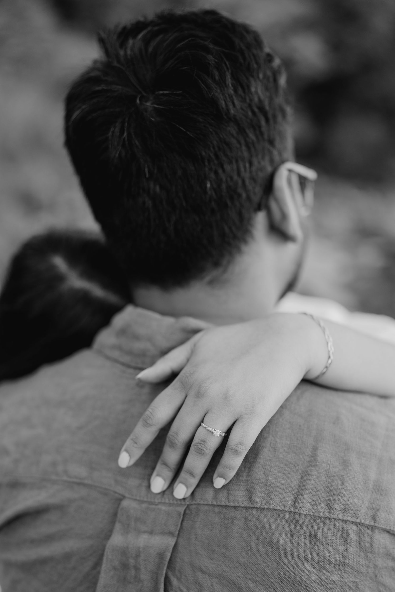 Black and white engagement photo of couple embracing from behind