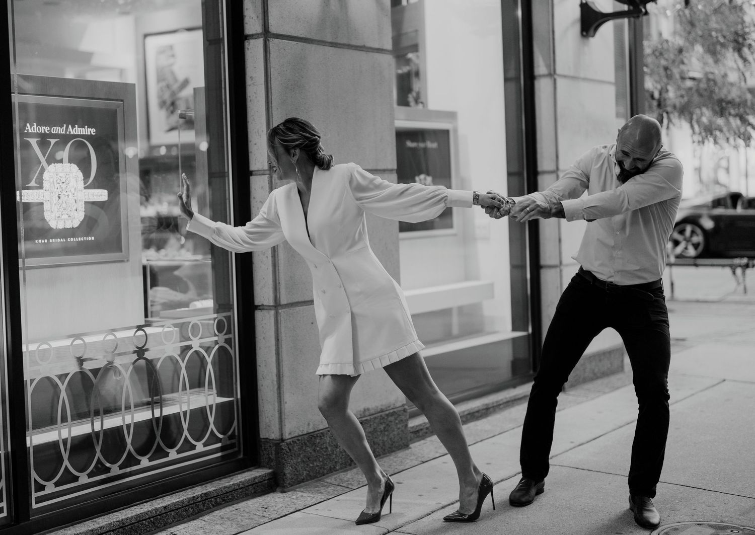 Candid black and white engagement shot of couple being playful in the city