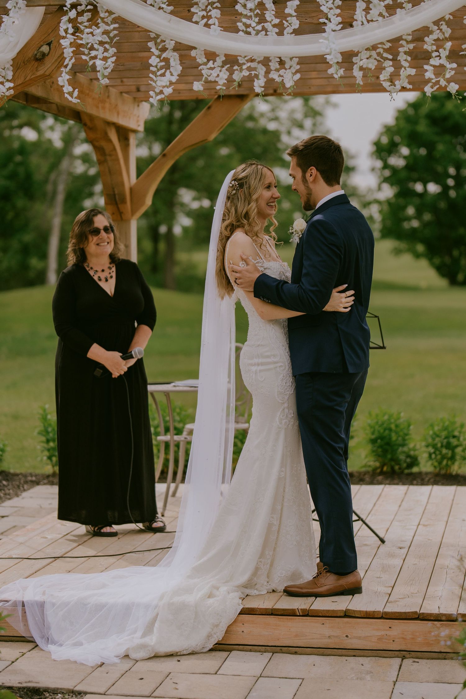 Bride and groom exchanging vows under floral arch with officiant