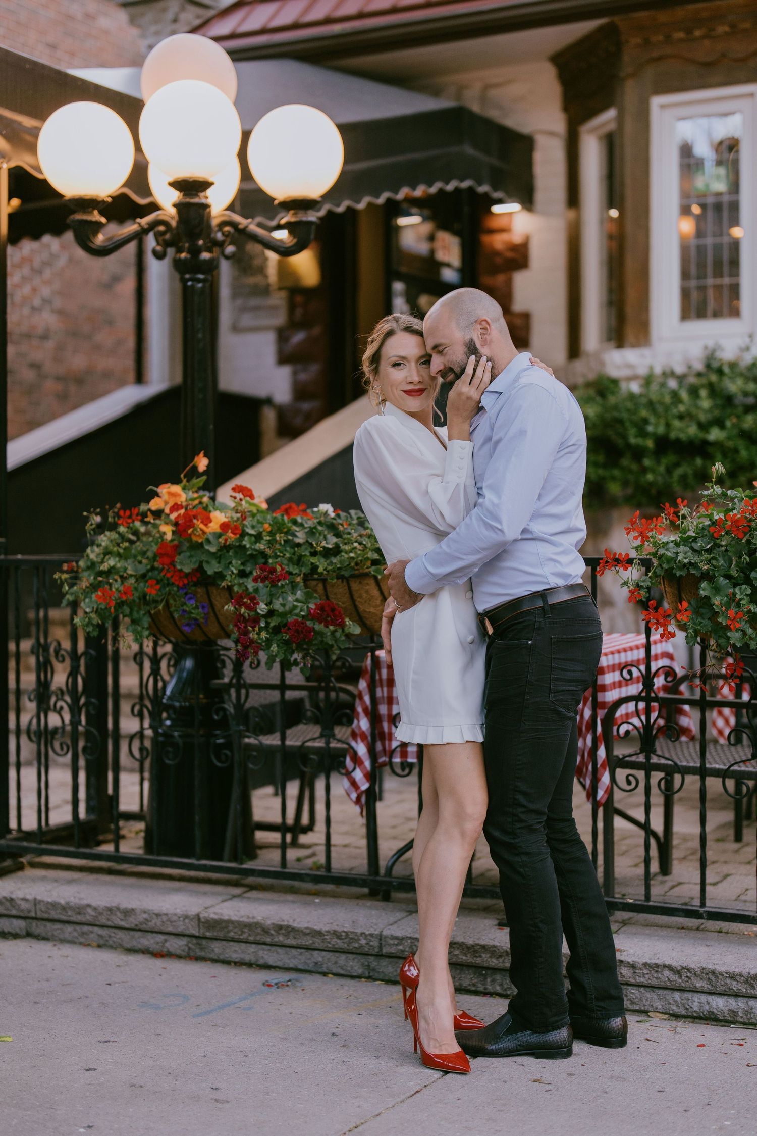 Elegant couple sharing a tender moment under cafe globe lights in the city