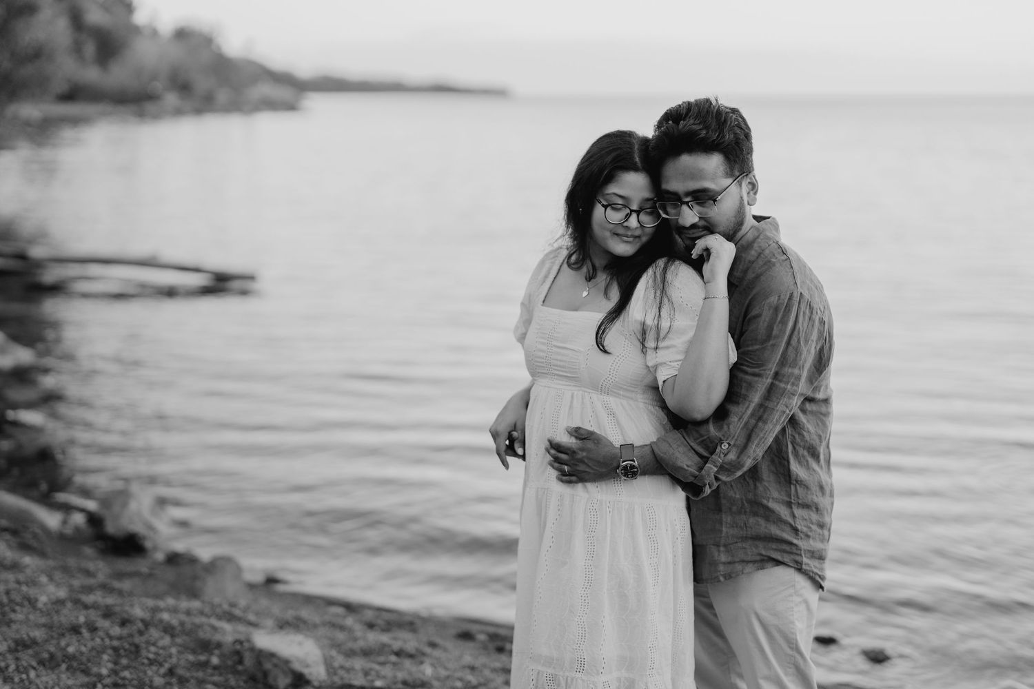 Black and white romantic moment of groom kissing bride on the temple near water