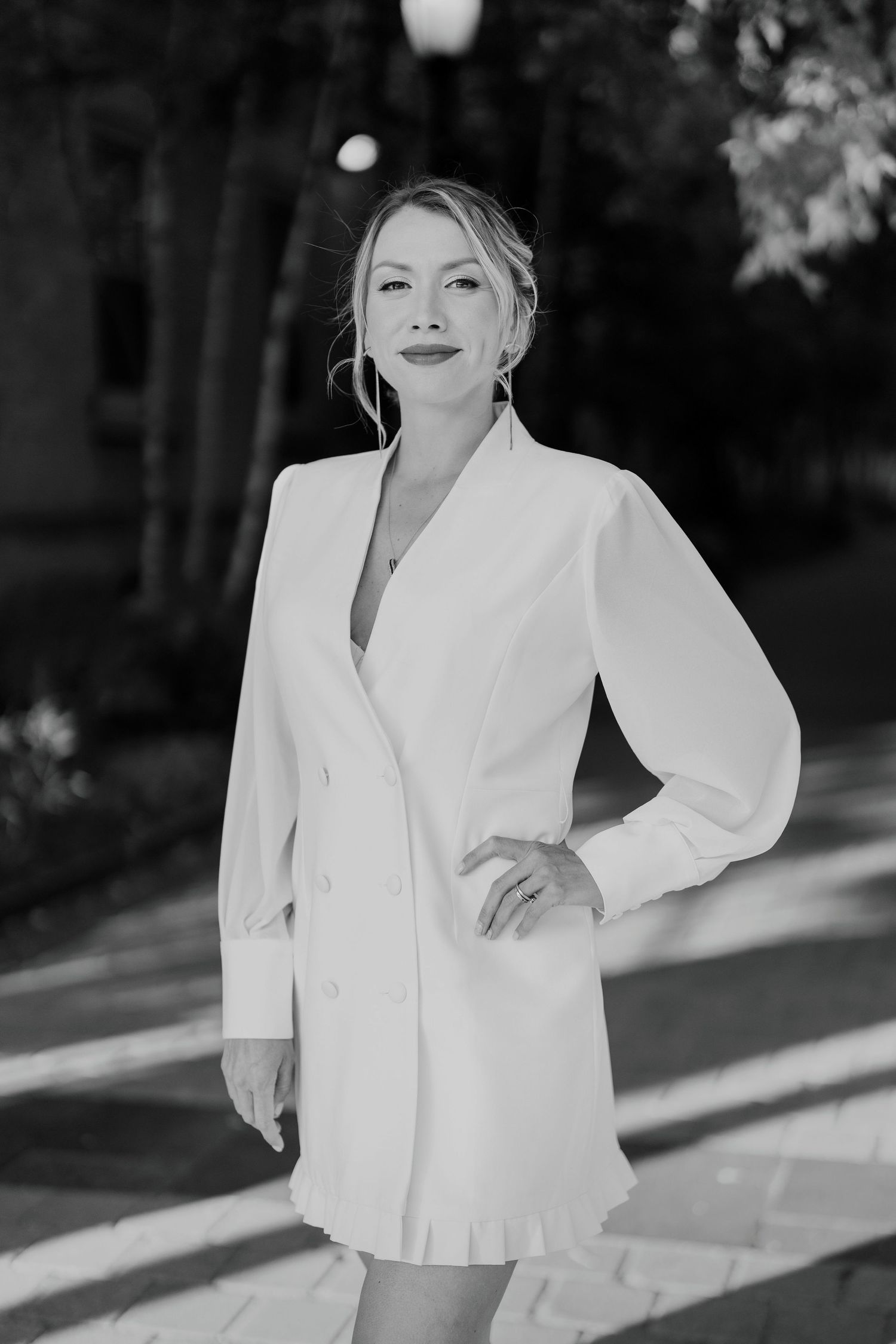 Stylish black and white portrait of woman in a white blazer dress, posing confidently