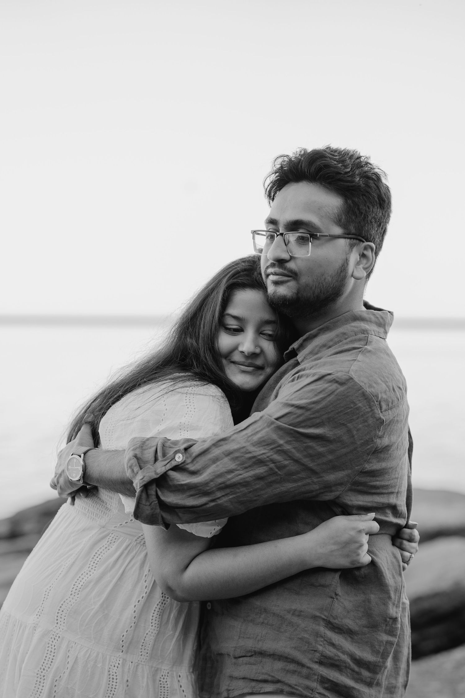 Black and white photo of couple in a tight embrace near the lake