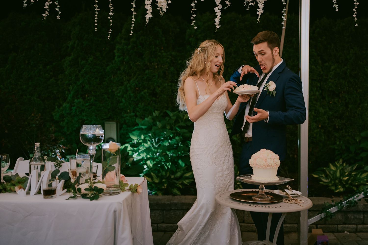 Groom feeding bride wedding cake during reception with smiles