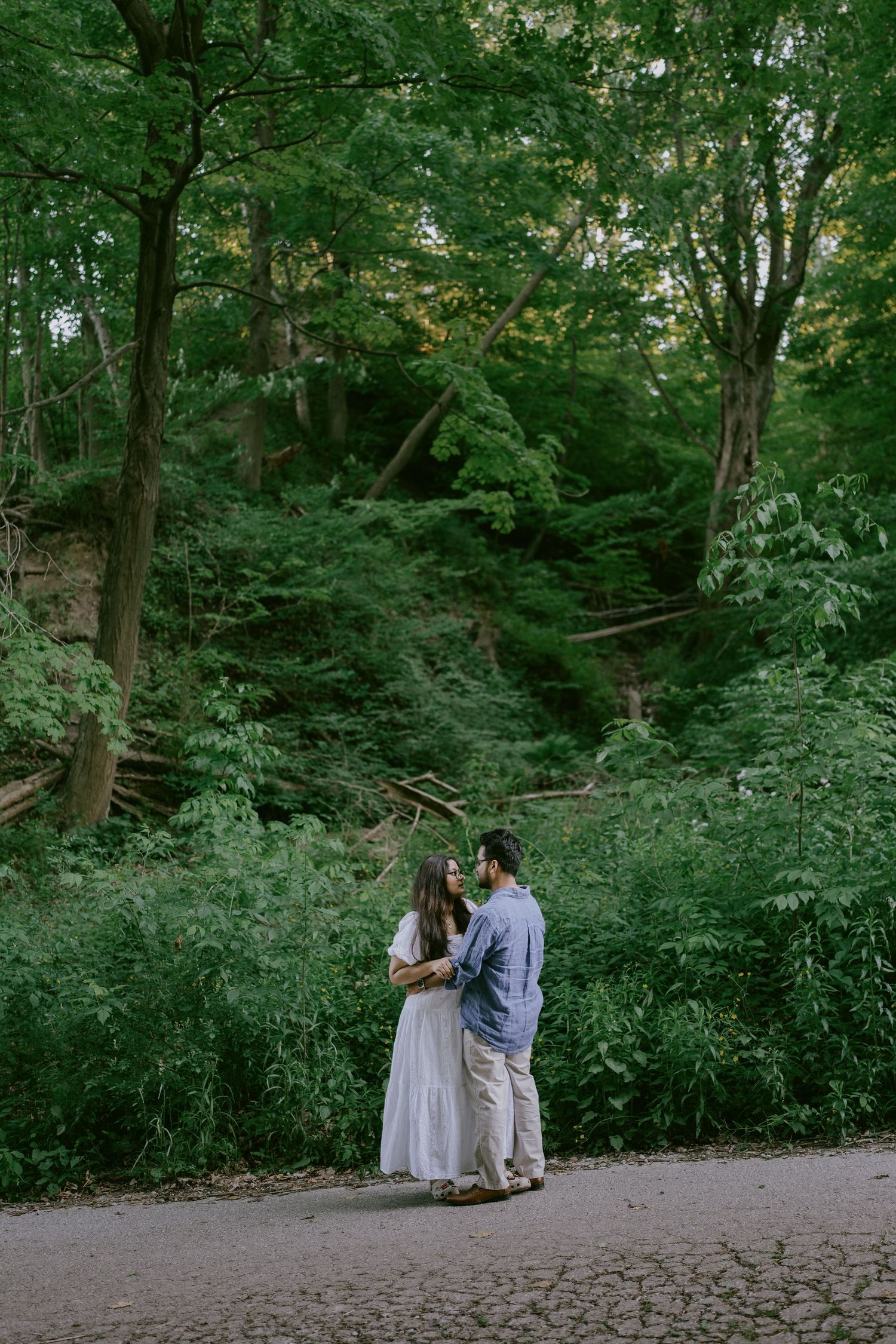 Romantic engagement portrait of couple embracing in a forest clearing