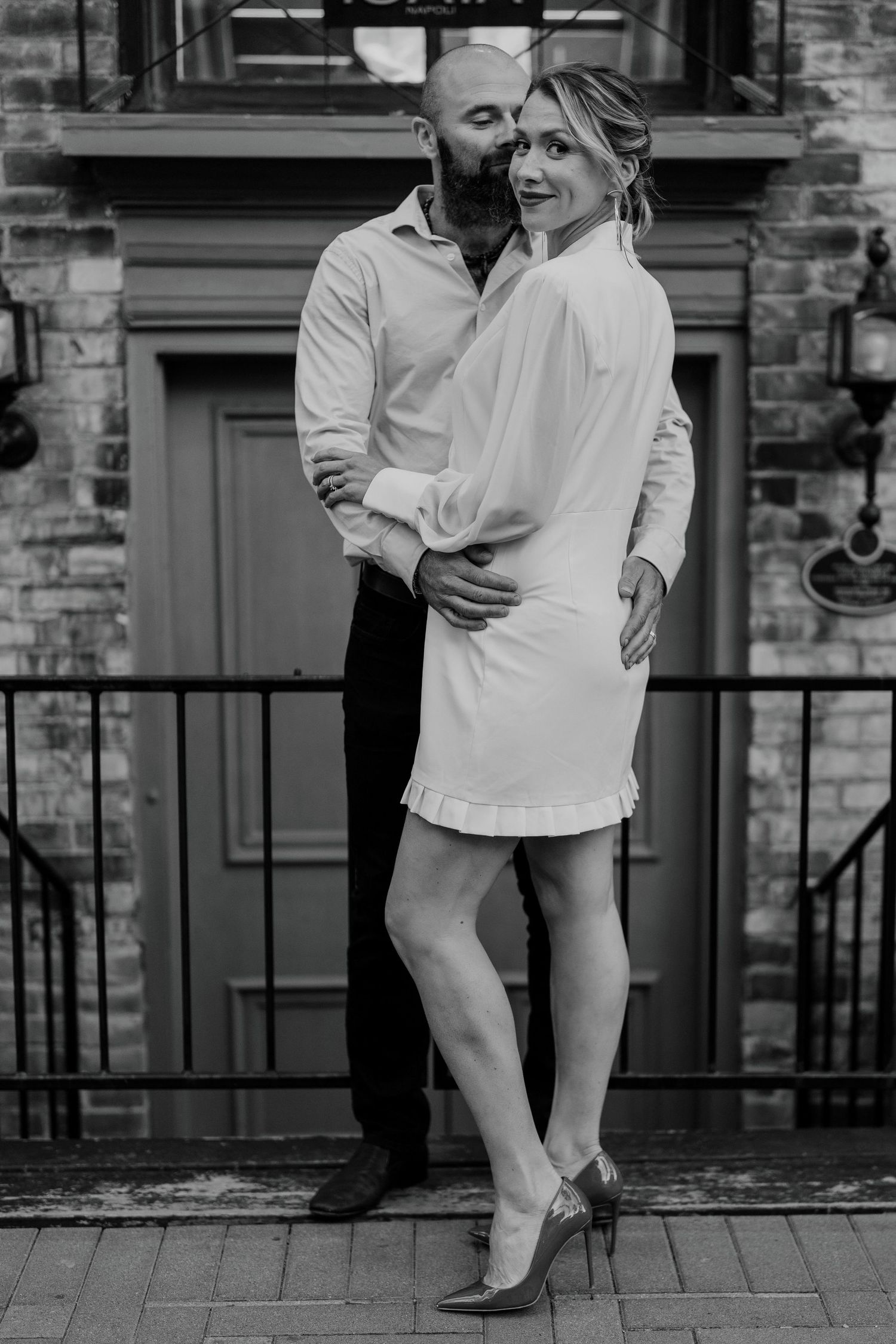 Candid black and white wedding photo of couple laughing together near city railing