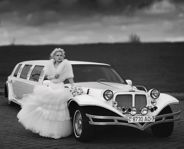 Vintage-inspired black and white photo of bride standing by a classic white limousine in Oshawa, Ontario, available throughout Toronto