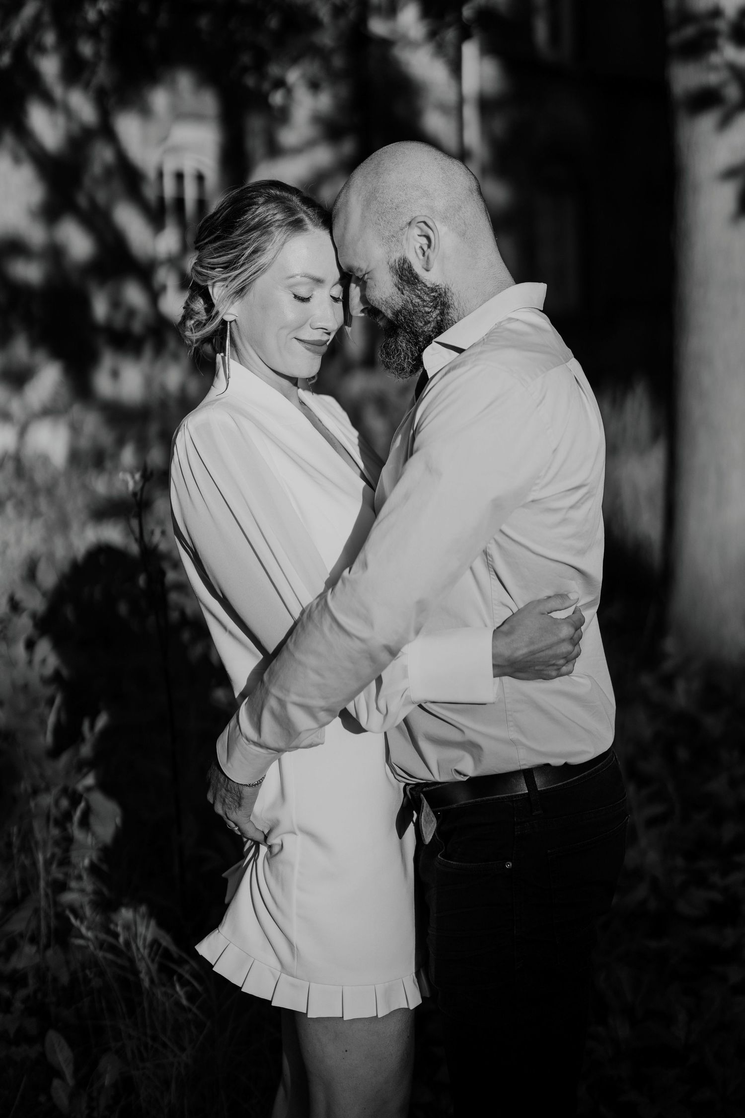 Black and white portrait of couple embracing under soft garden light