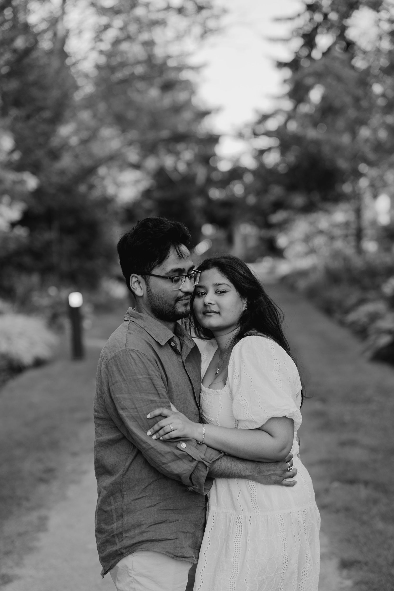 Black and white romantic photo of couple hugging on forested path