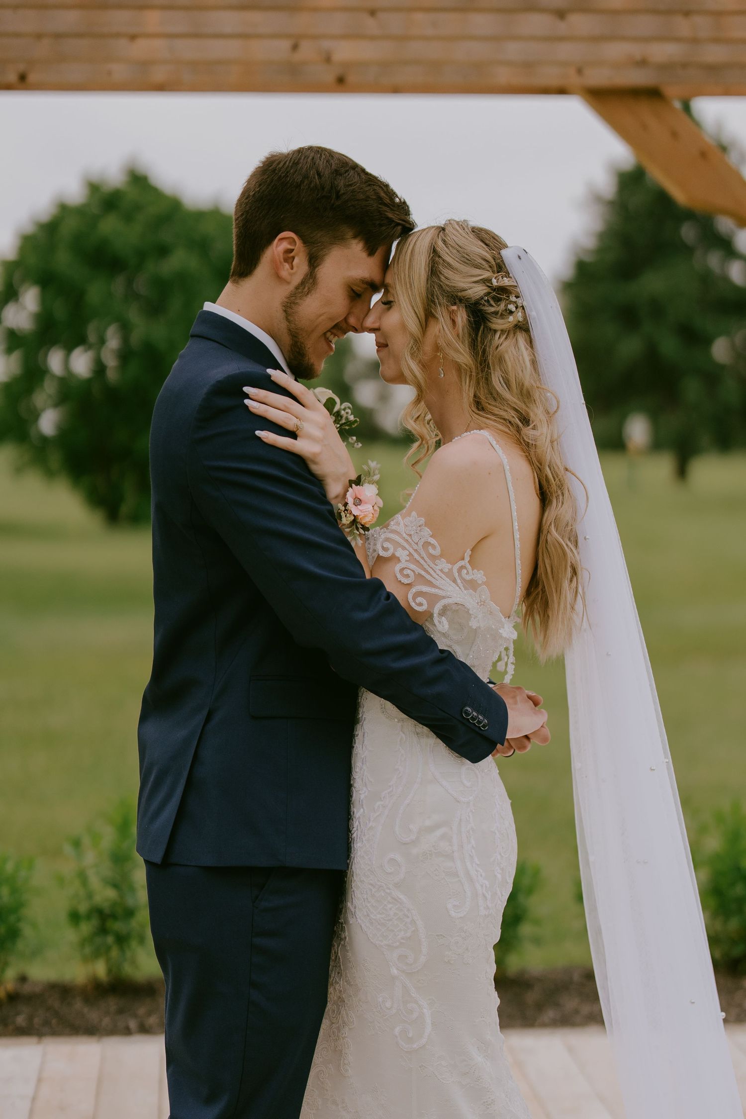Bride and groom sharing intimate moment under wooden wedding arch