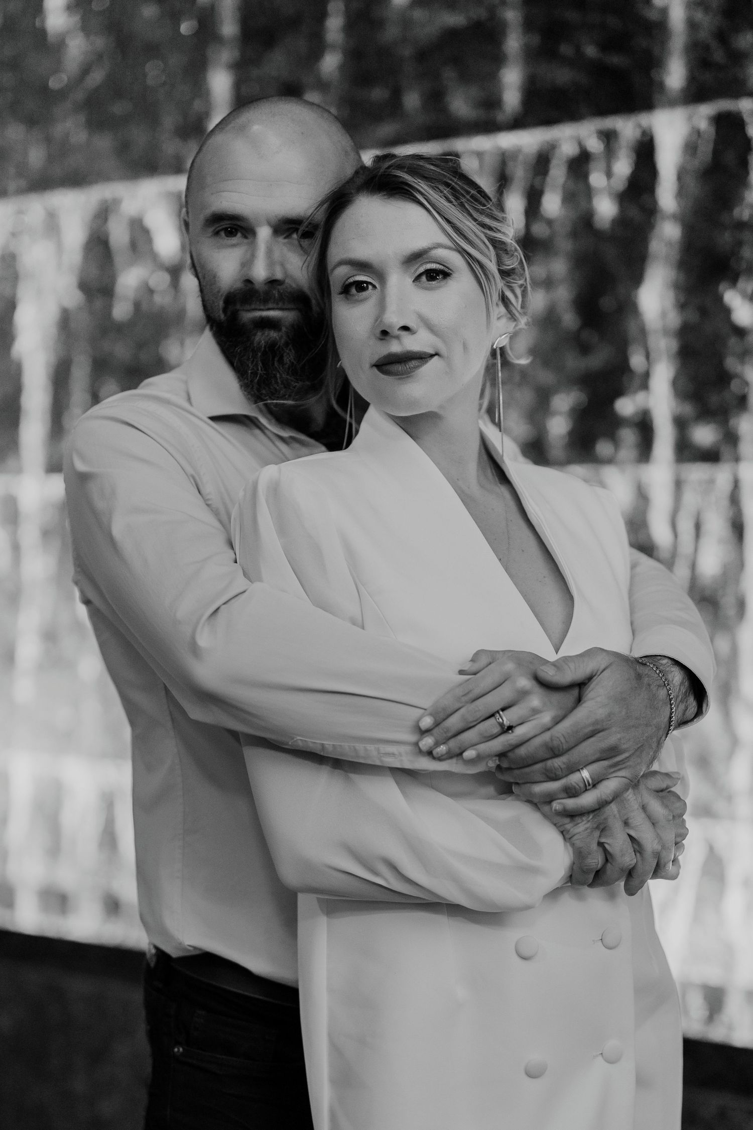 Black and white wedding portrait of couple embracing in front of stone wall
