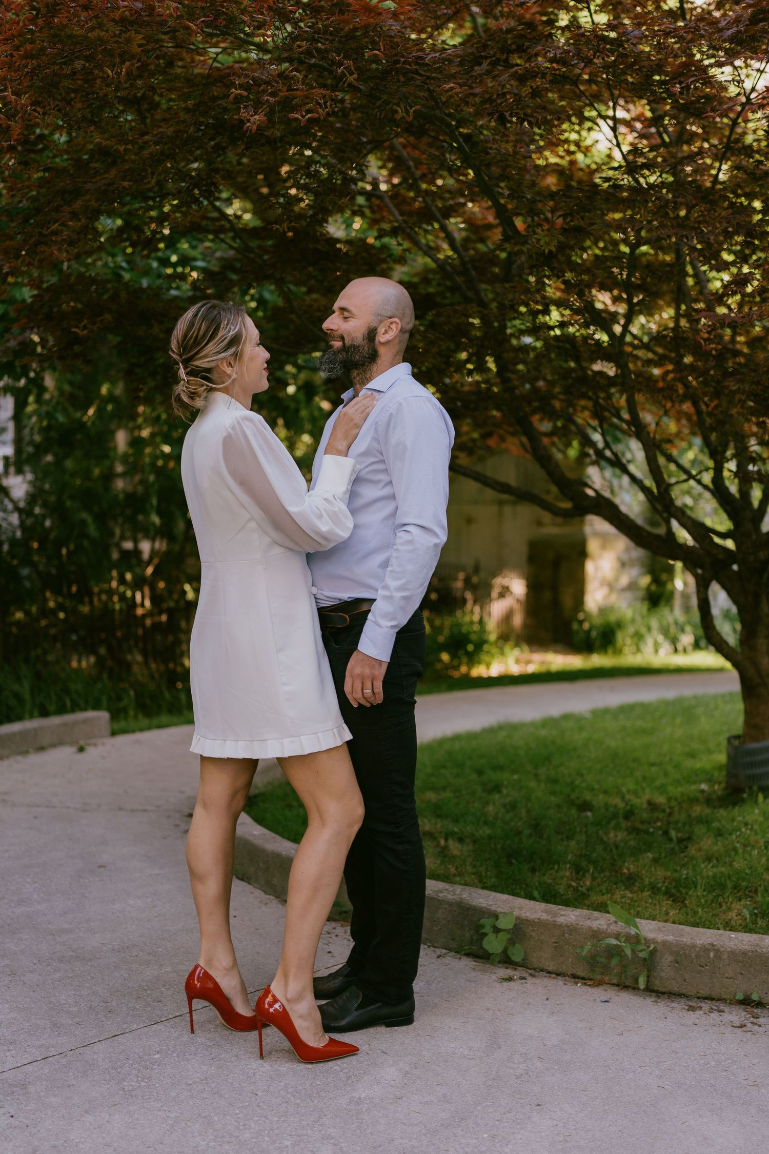 Candid wedding photo of couple laughing under tree in afternoon light