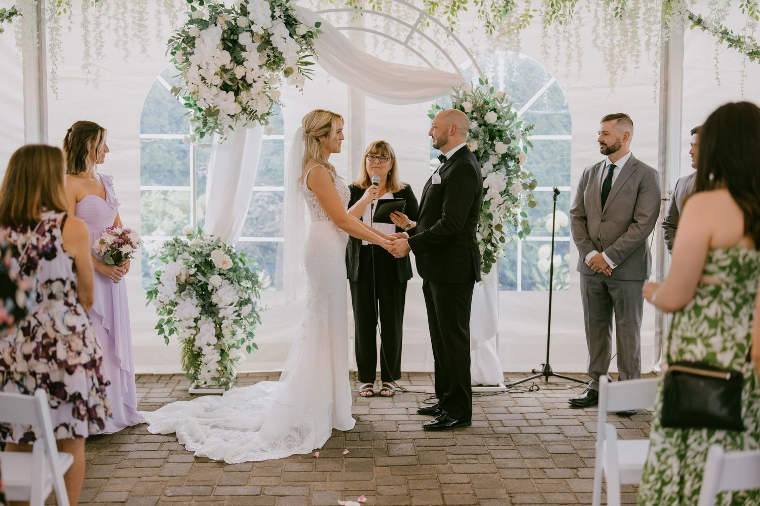 Emotional wedding ceremony with bride and groom exchanging vows under floral arch  in Oshawa, available throughout Toronto and Durham region