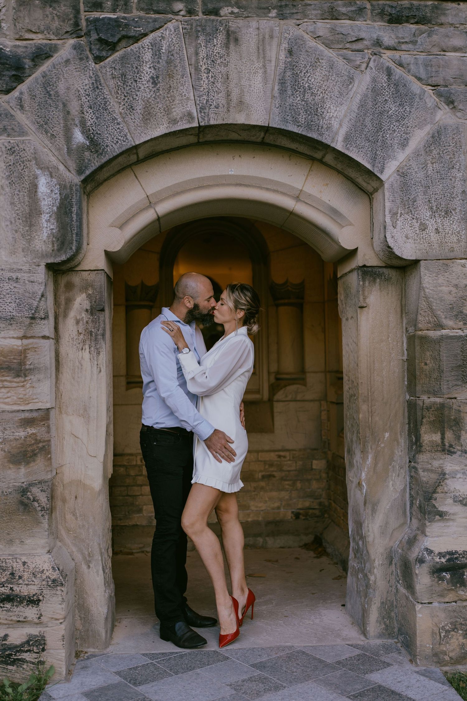 Intimate engagement photo of couple standing in gothic stone archway