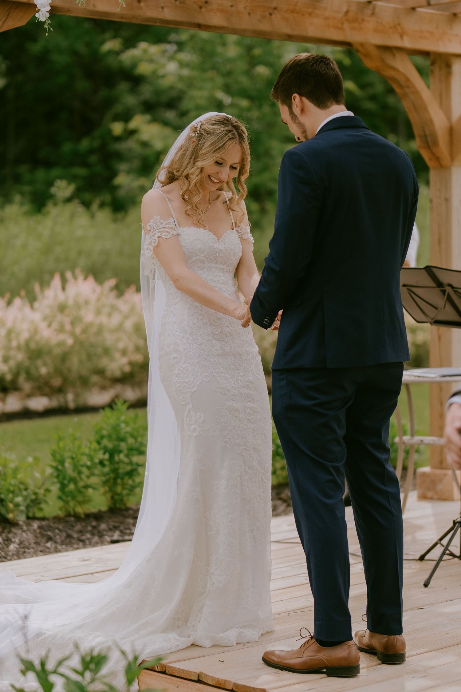 Bride and groom reading vows during ceremony under wooden arch