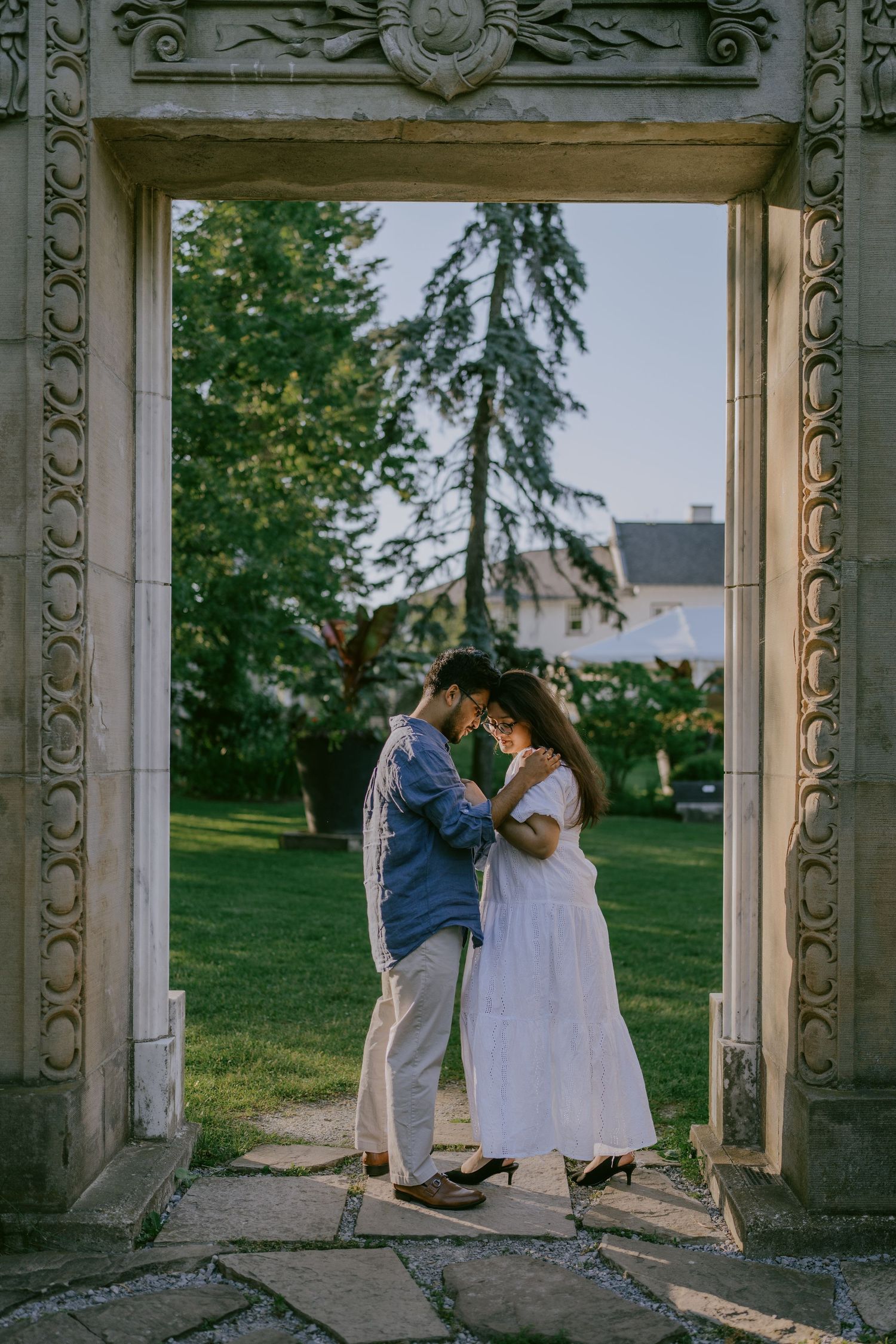 Romantic photo of couple kissing under stone arch at historic park