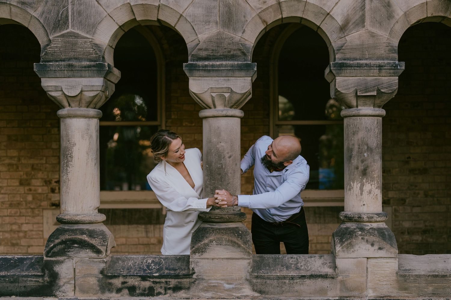 Creative wedding photo of couple interacting between castle-style stone columns
