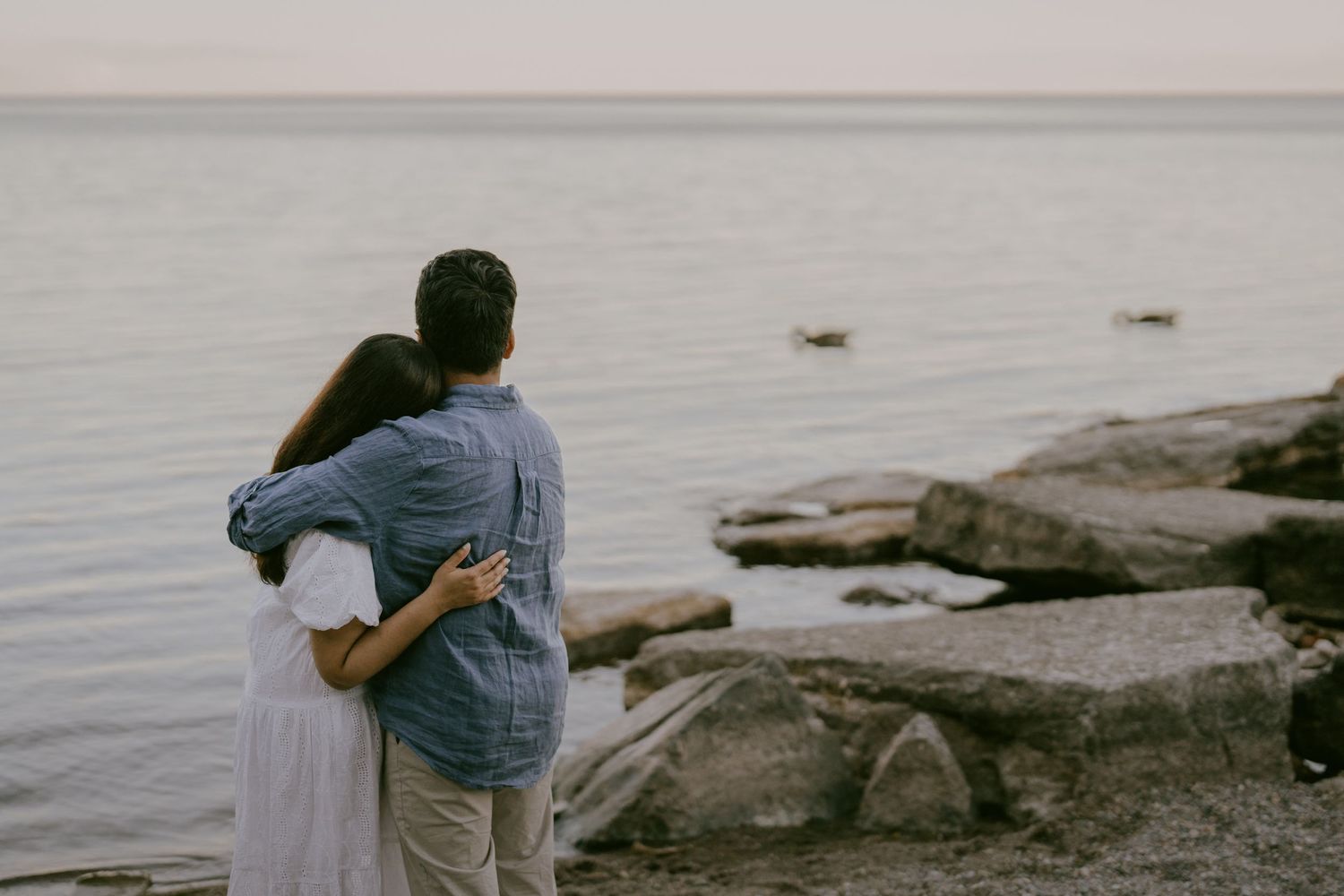 Black and white engagement photo of couple looking out over lake