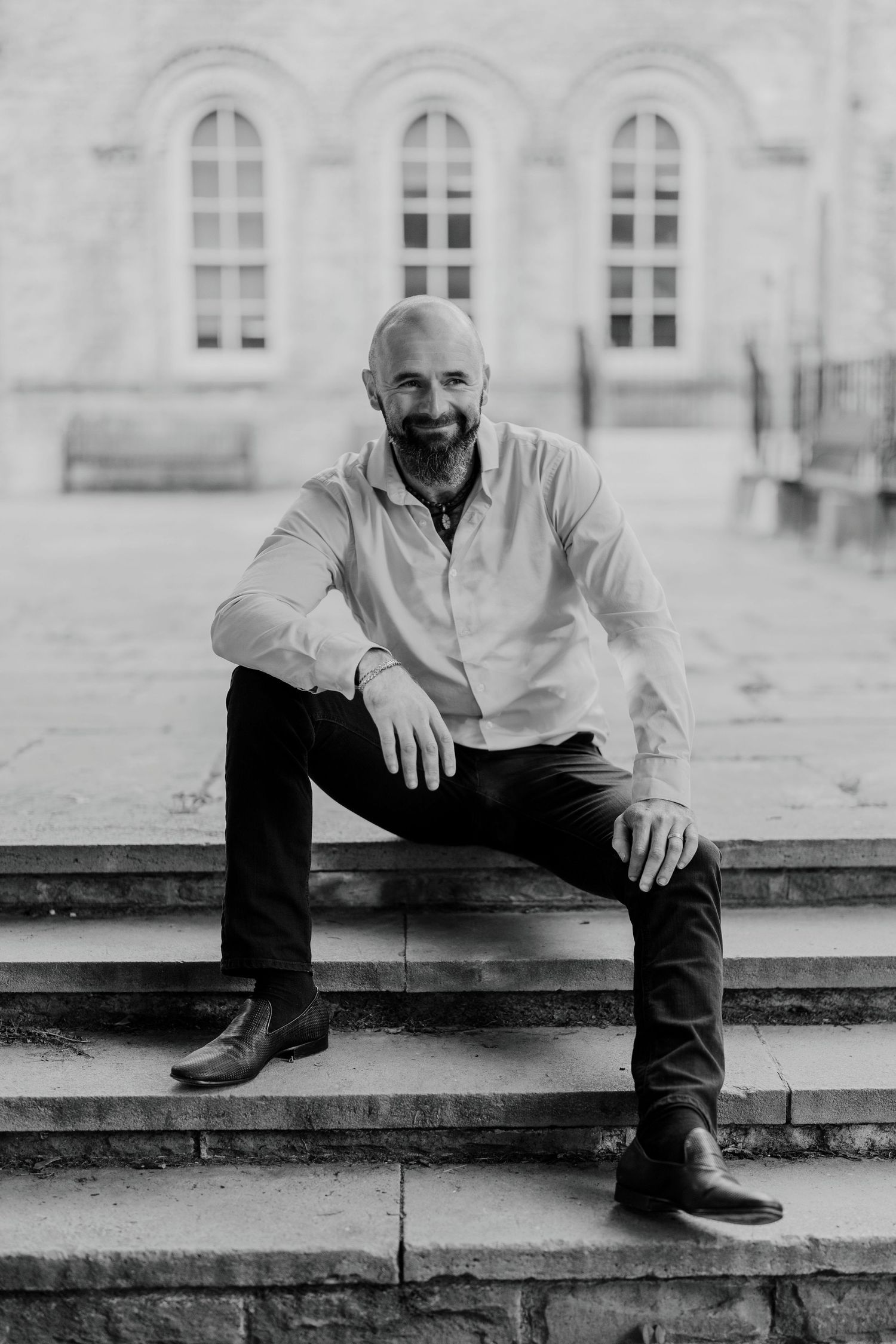 Candid black and white portrait of man sitting on stone steps, smiling naturally
